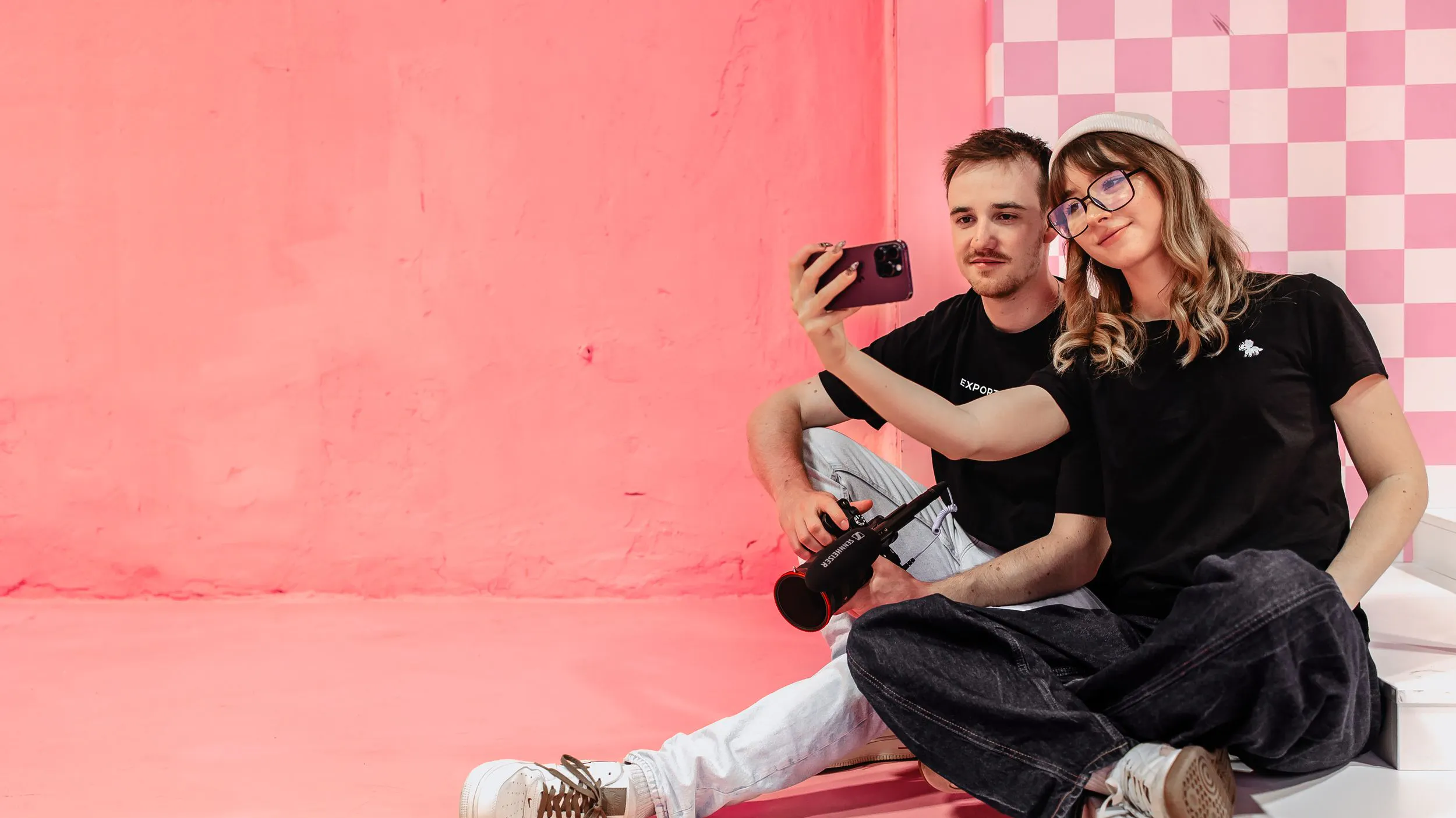 Zwei Mitarbeiter der Kasseler Social Media Agentur Exportarts machen ein Selfie vor einer pinken Wand