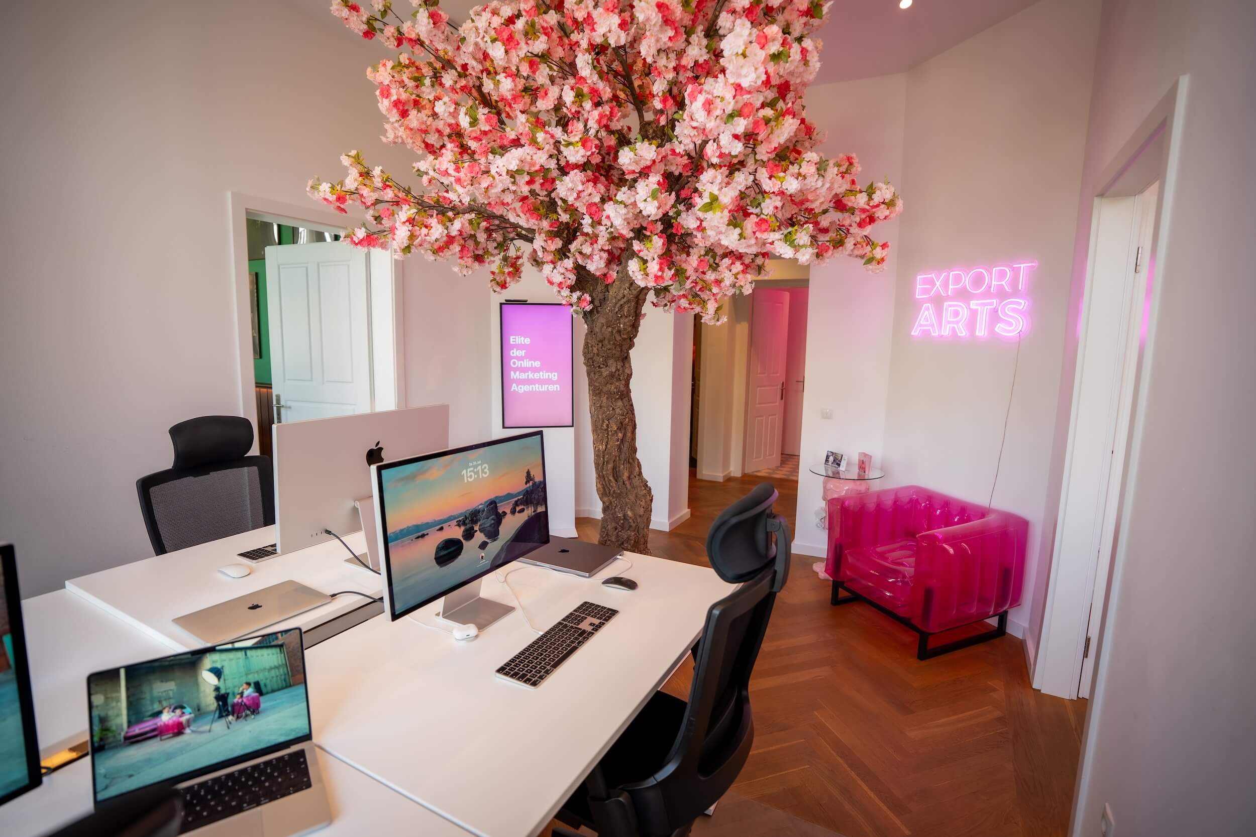 Büro im Exportarts Office mit großem Tisch und pinkem Kunstbaum als zentrales Element