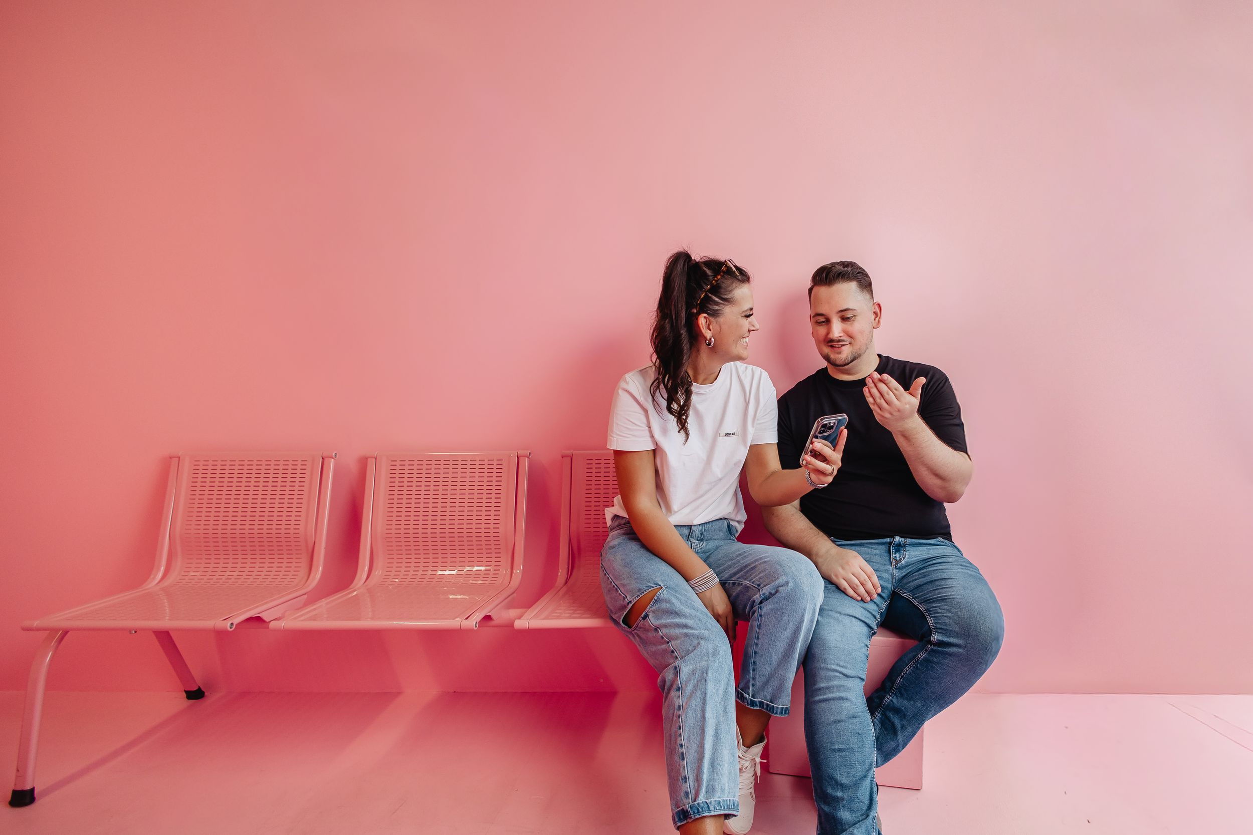 Zwei Mitarbeiter der Kasseler Social Media Agentur Exportarts sitzen vor einer pinken Wand und unterhalten sich