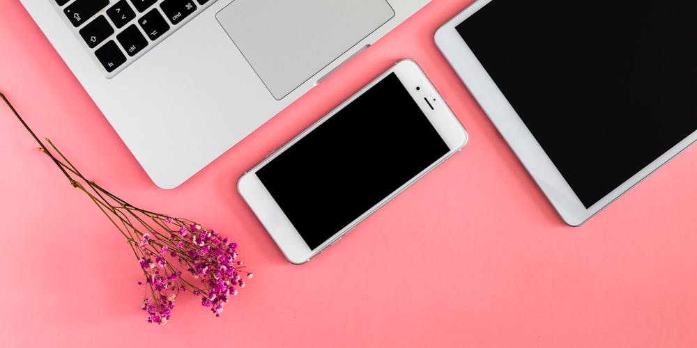 Laptop Tablet und Handy liegen auf pinkem Tisch Laptop Tablet und Handy liegen auf pinkem Tisch