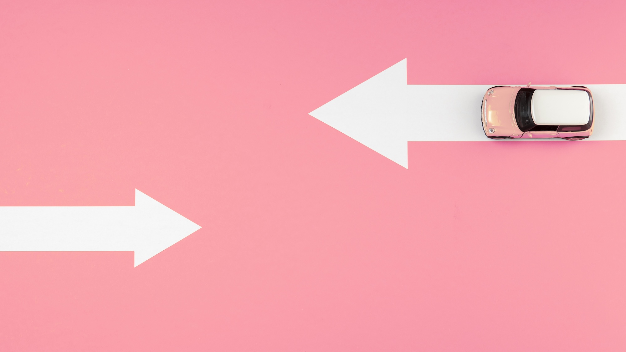 Auto auf weißen Pfeilen auf pinkem Hintergrund