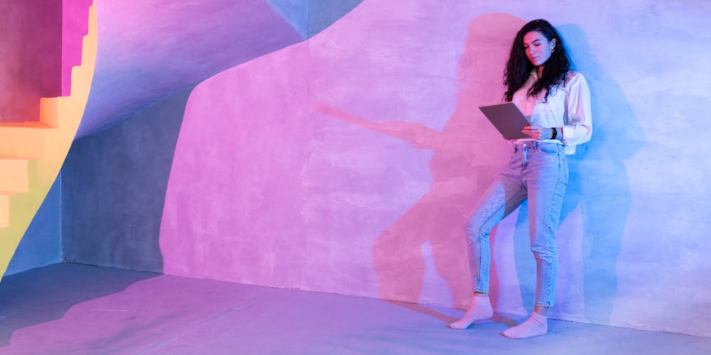 Frau mit Laptop lehnt sich an Wand Frau mit Laptop lehnt sich an Wand