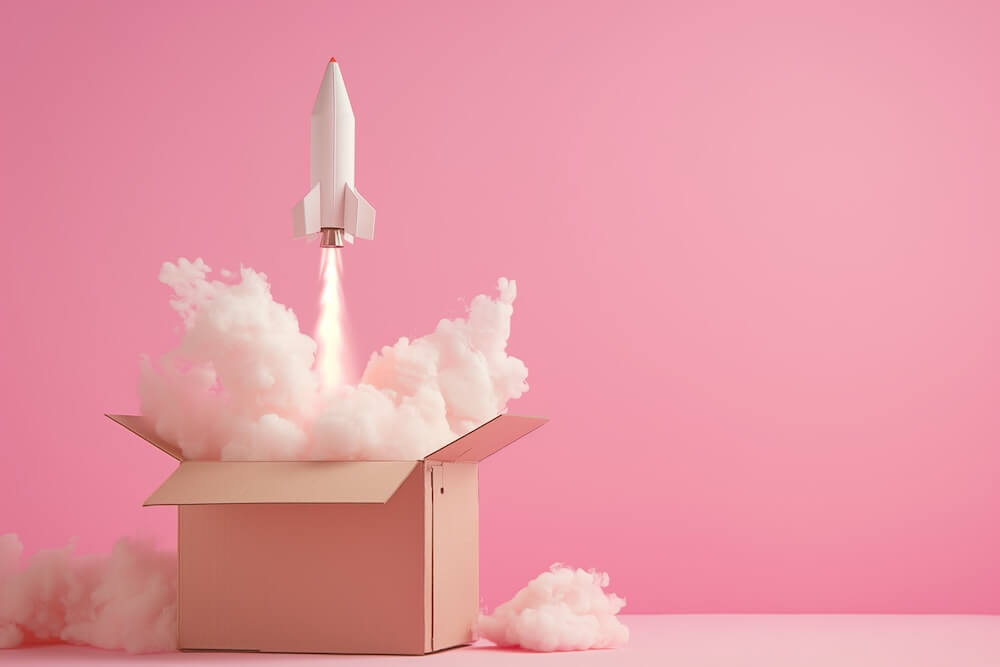 Rakete startet aus einem Karton vor pinkem Hintergrund