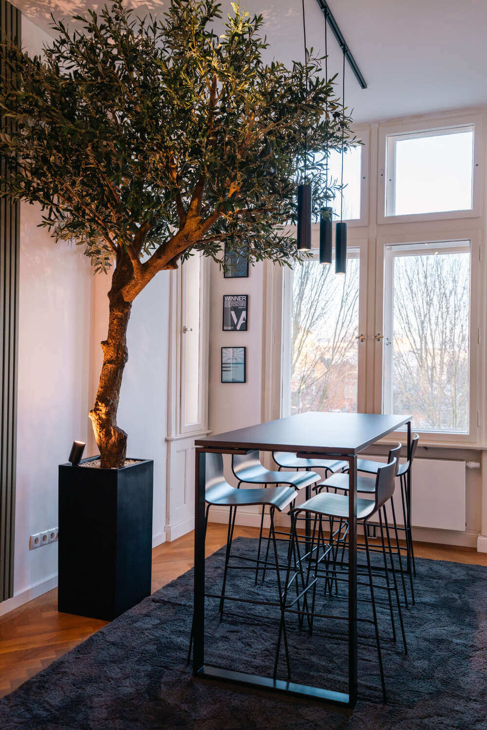 Meetingbereich im Exportarts Büro mit Stehtisch, Barhockern und dekorativem Baum