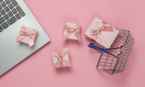 Kleine rosane Geschenke neben einem Macbook Kleine rosane Geschenke neben einem Macbook