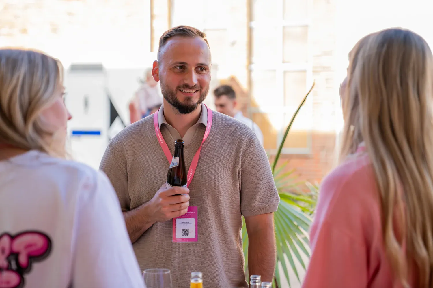 Networking-Gespräch zwischen drei Eventteilnehmern bei Sonnenuntergang im Außenbereic