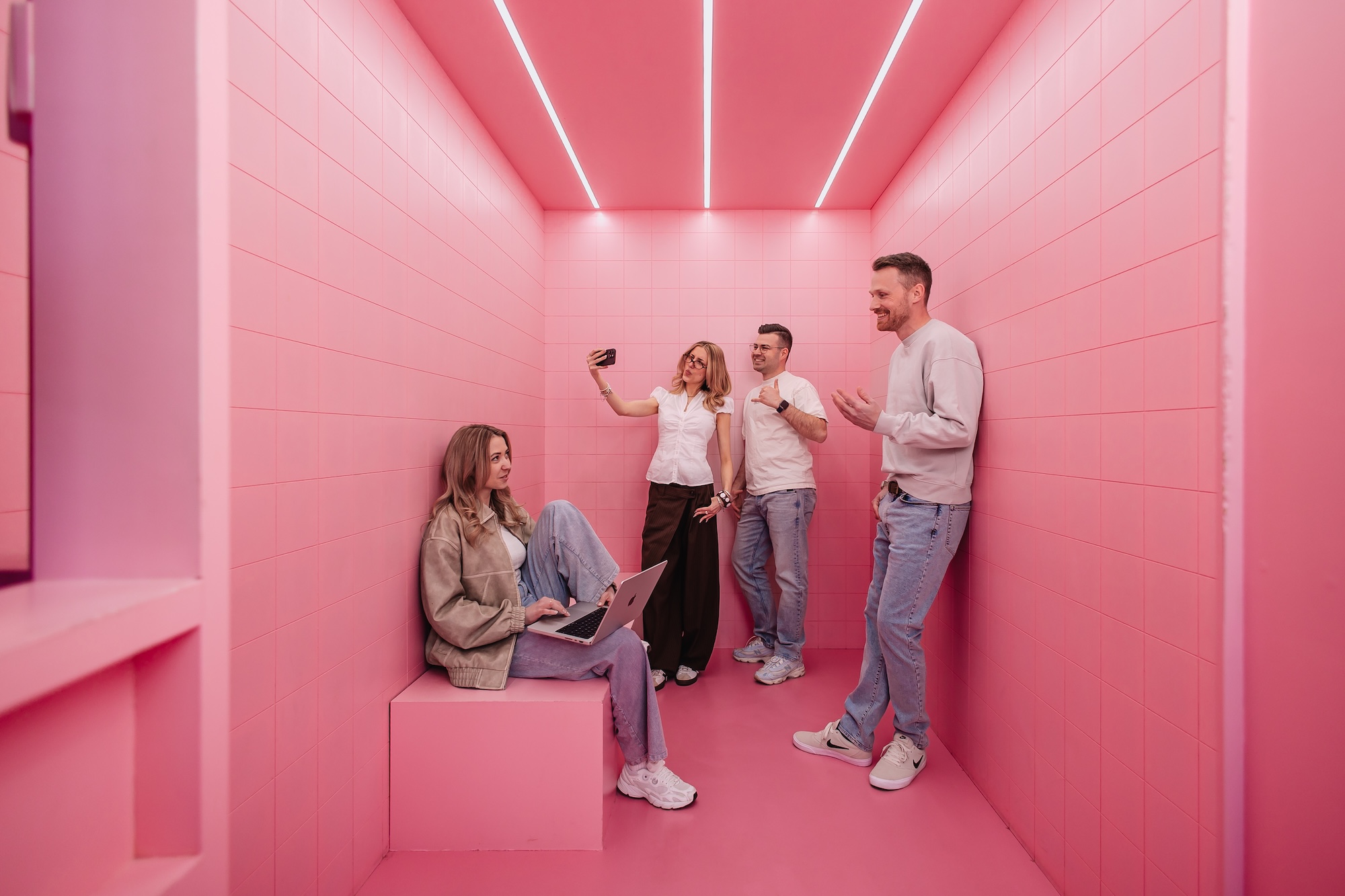 Vier Mitarbeiter der SEO Agentur Exportarts posieren in einem pinken Raum