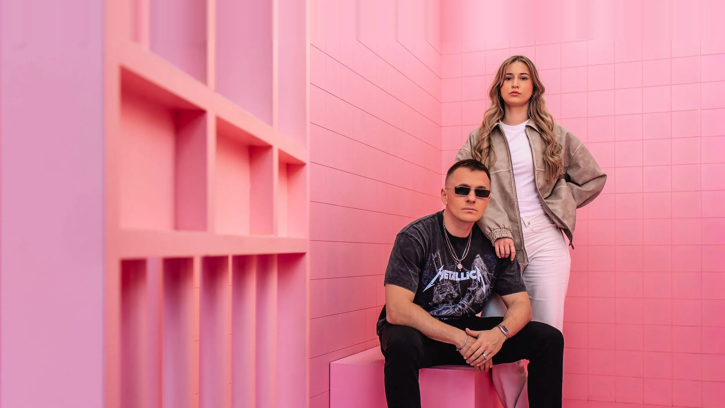 Team der GEO Agentur Exportarts – zwei Personen mit Sonnenbrille vor pinkfarbener Kulisse