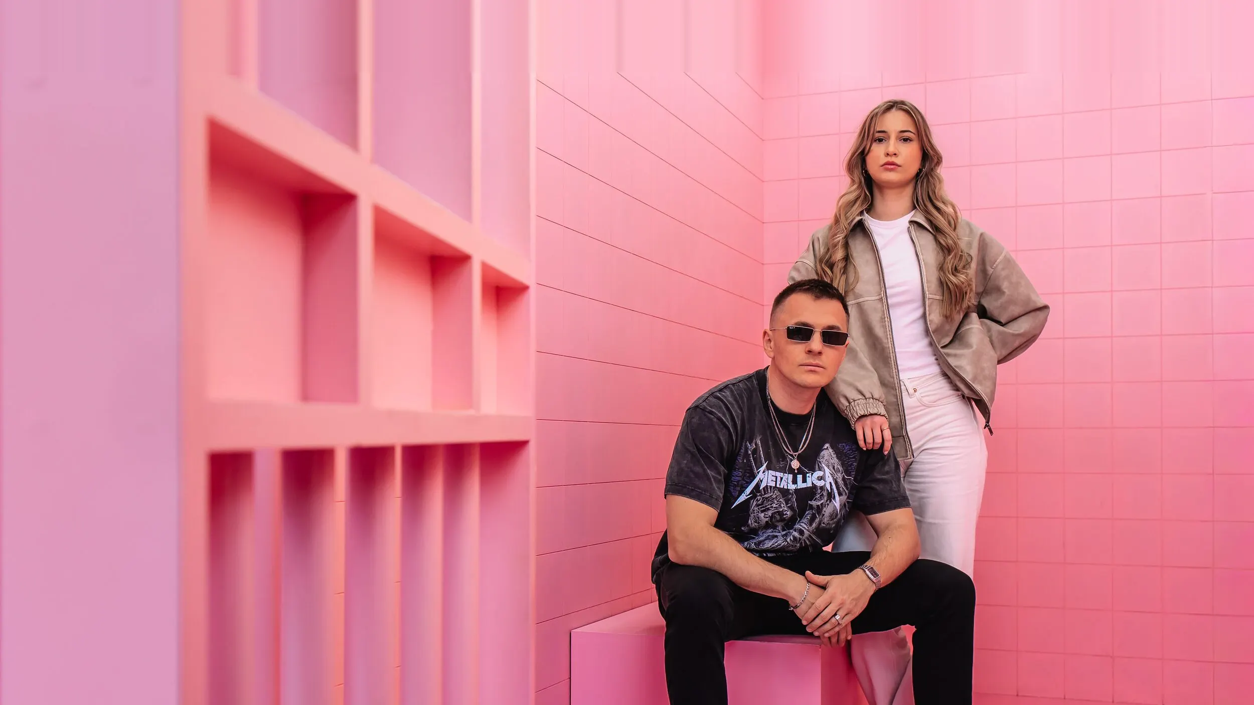 Team der GEO Agentur Exportarts – zwei Personen mit Sonnenbrille vor pinkfarbener Kulisse