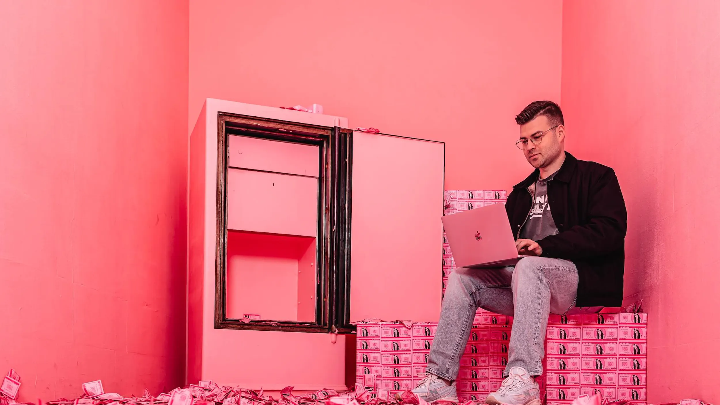 Mitarbeiter der Bing Agentur Exportarts sitzt in einem pinken Tresor und arbeitet an einem Macbook