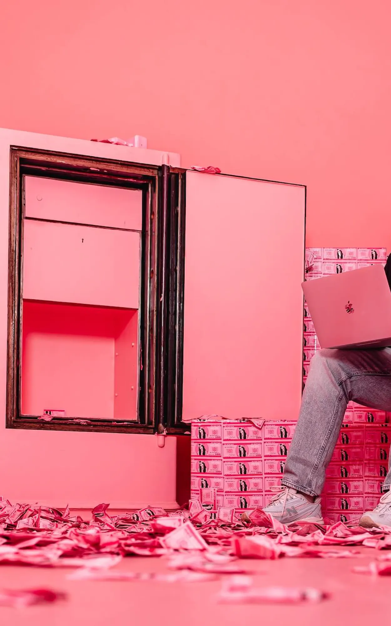 Luca von der Agentur Exportarts sitzt in einem pinken Tresor und arbeitet an einem Macbook
