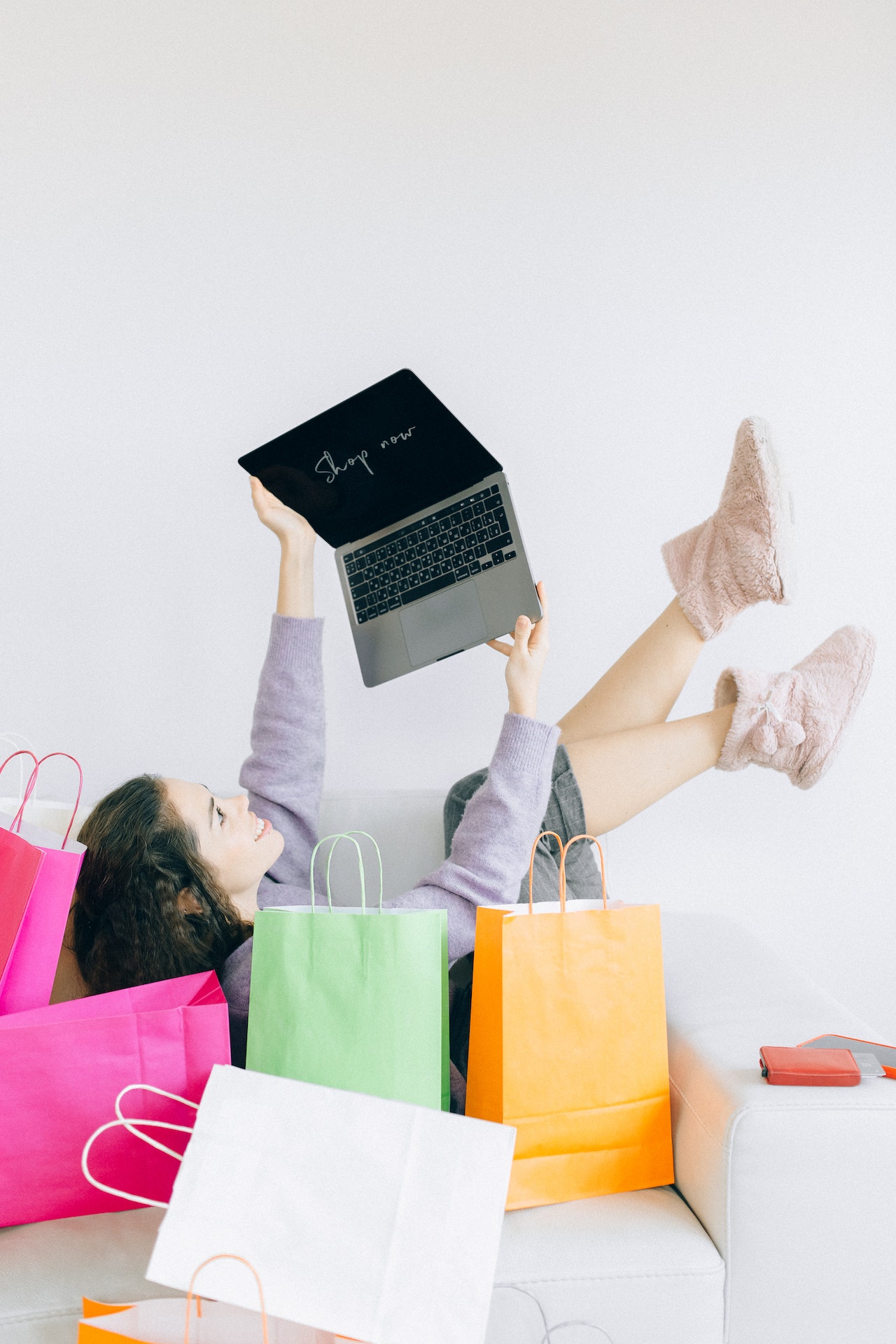 Frau mit Laptop zwischen Shopping Tüten