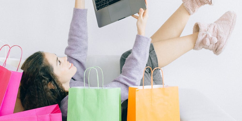 Frau mit Laptop zwischen Shopping Tüten Frau mit Laptop zwischen Shopping Tüten