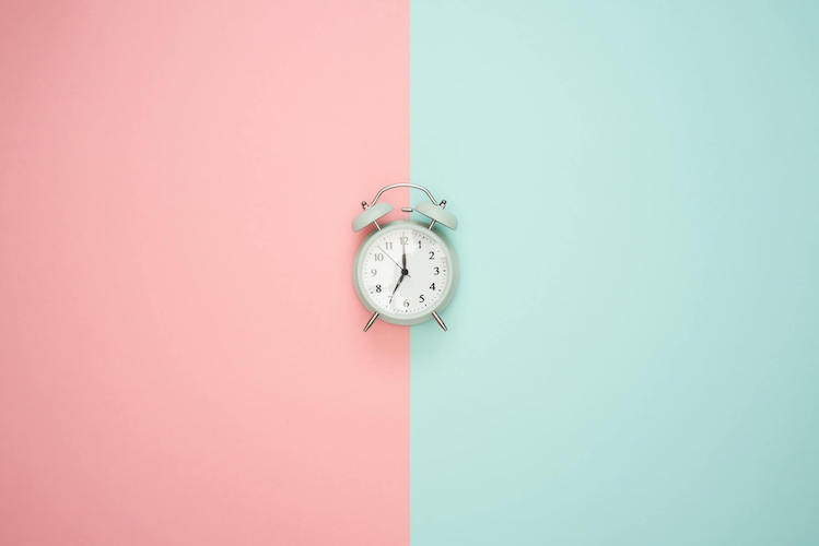 Wecker vor pink türkisem Hintergrund