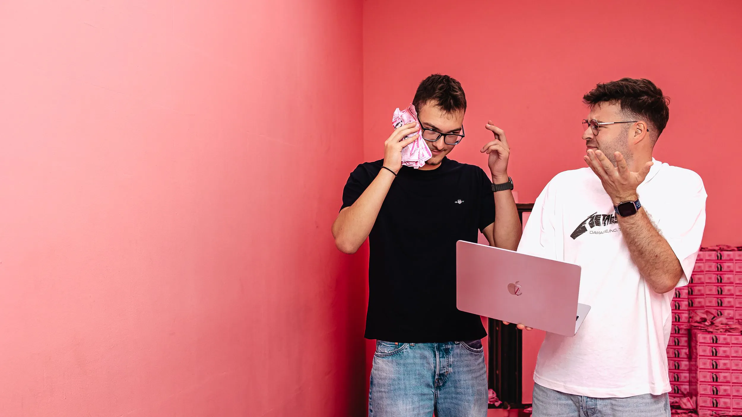 Zwei Mitarbeiter der Performance Marketing Agentur Exportarts mit pinkem Geld und Macbook in der Hand