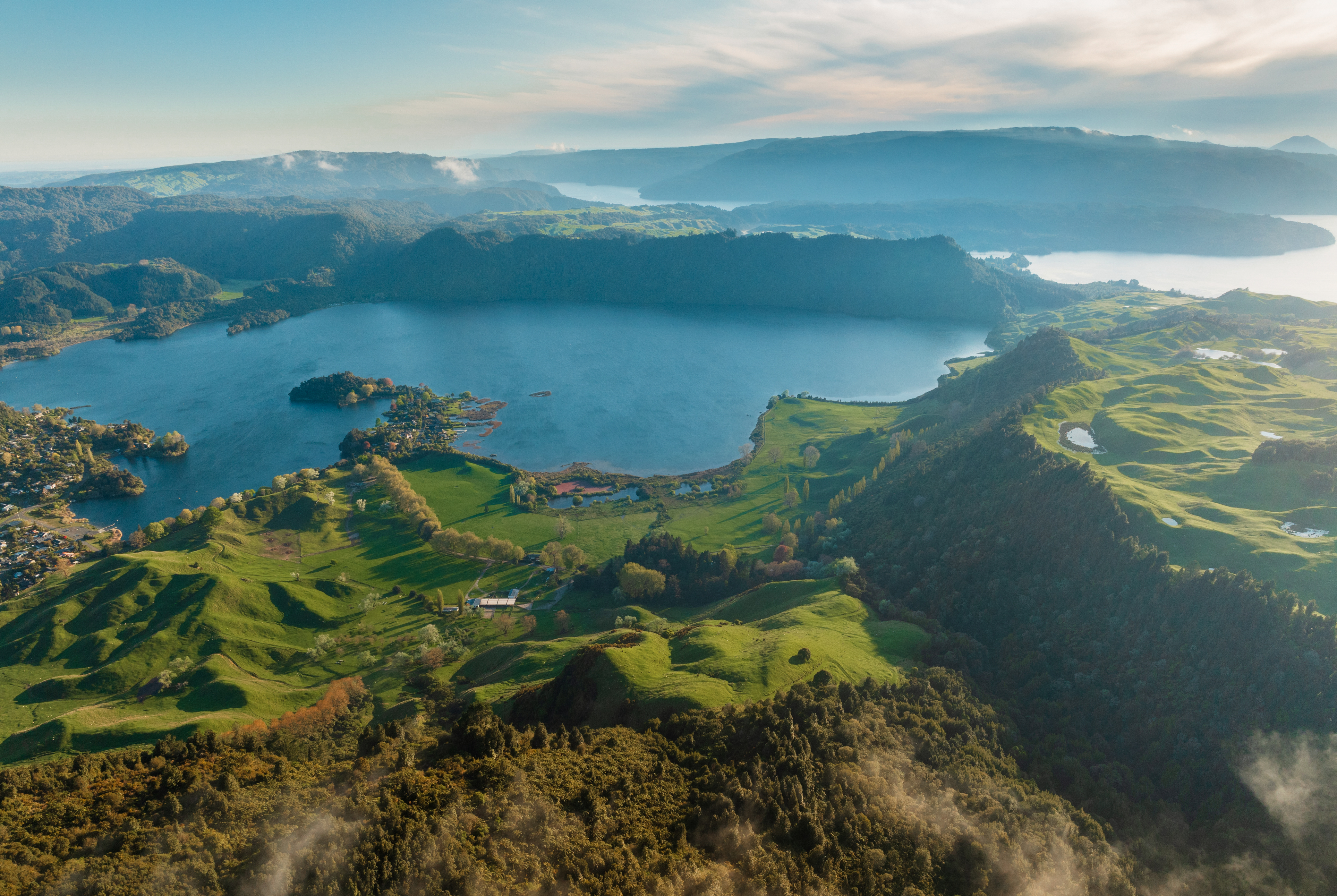 Aerial view of crater lake surrounded by green hills, Rotorua New Zealand