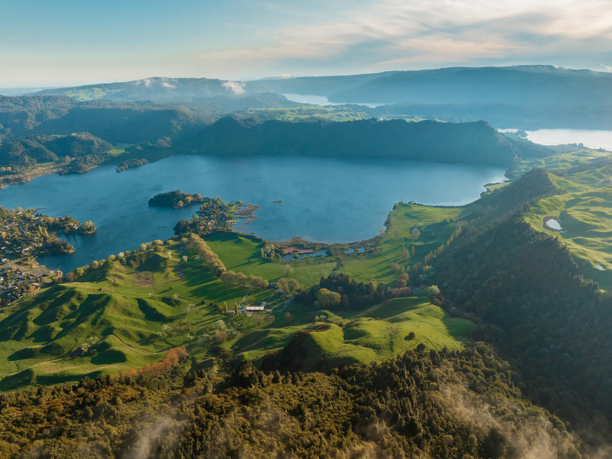 Aerial view of crater lake surrounded by green hills, Rotorua New Zealand