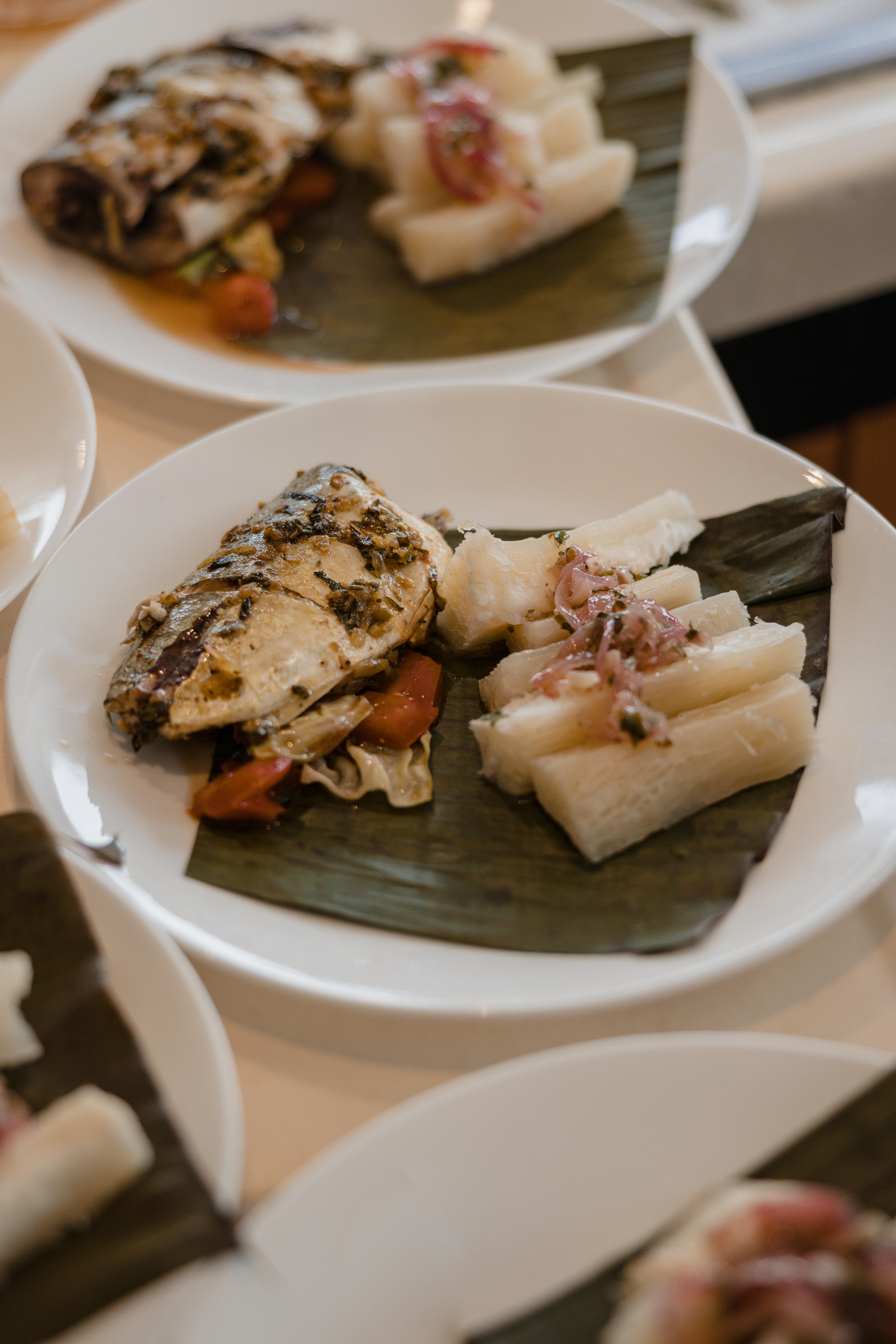 Grilled fish and yuca with pickled onions served on a banana leaf in Panama