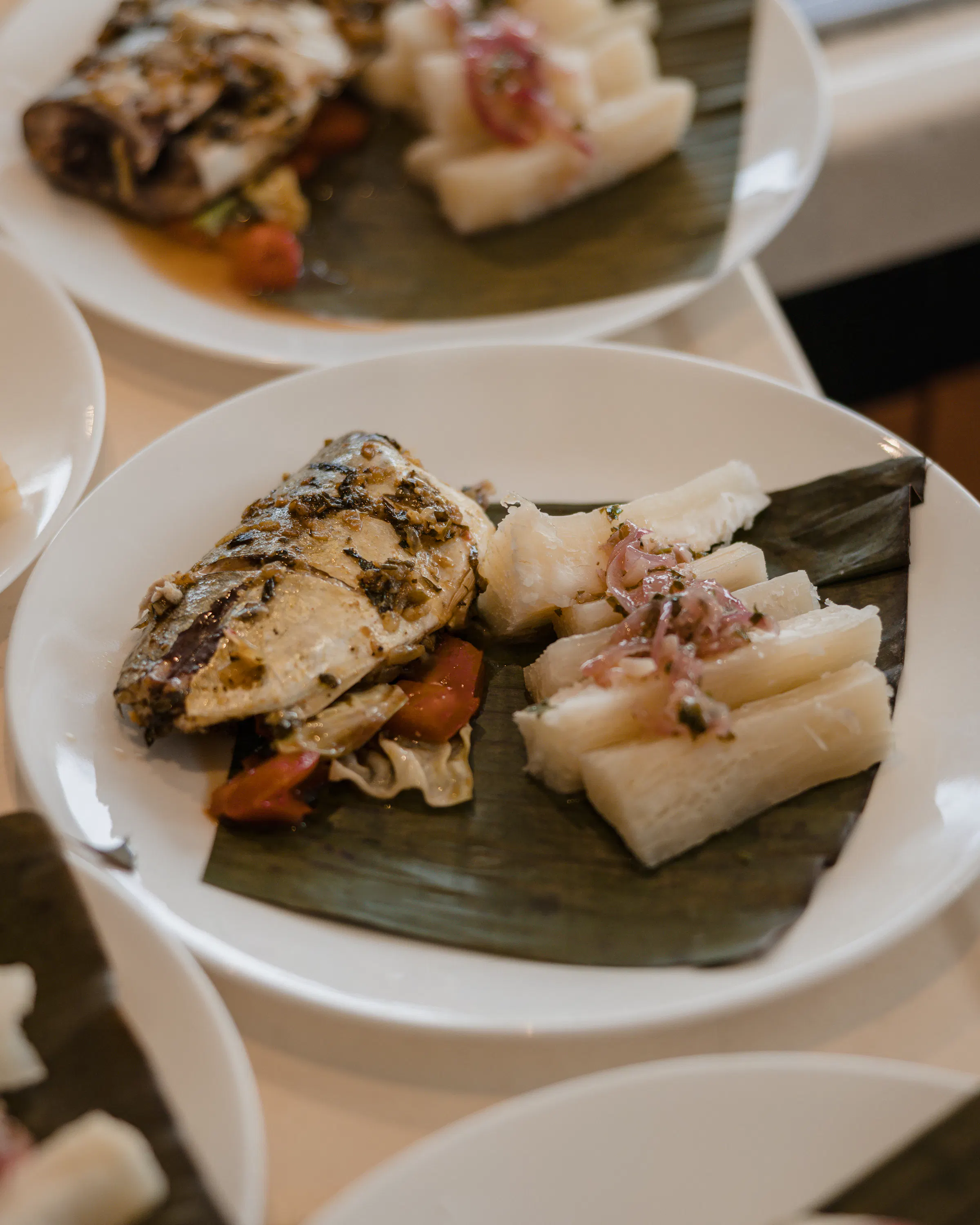 Grilled fish and yuca with pickled onions served on a banana leaf in Panama