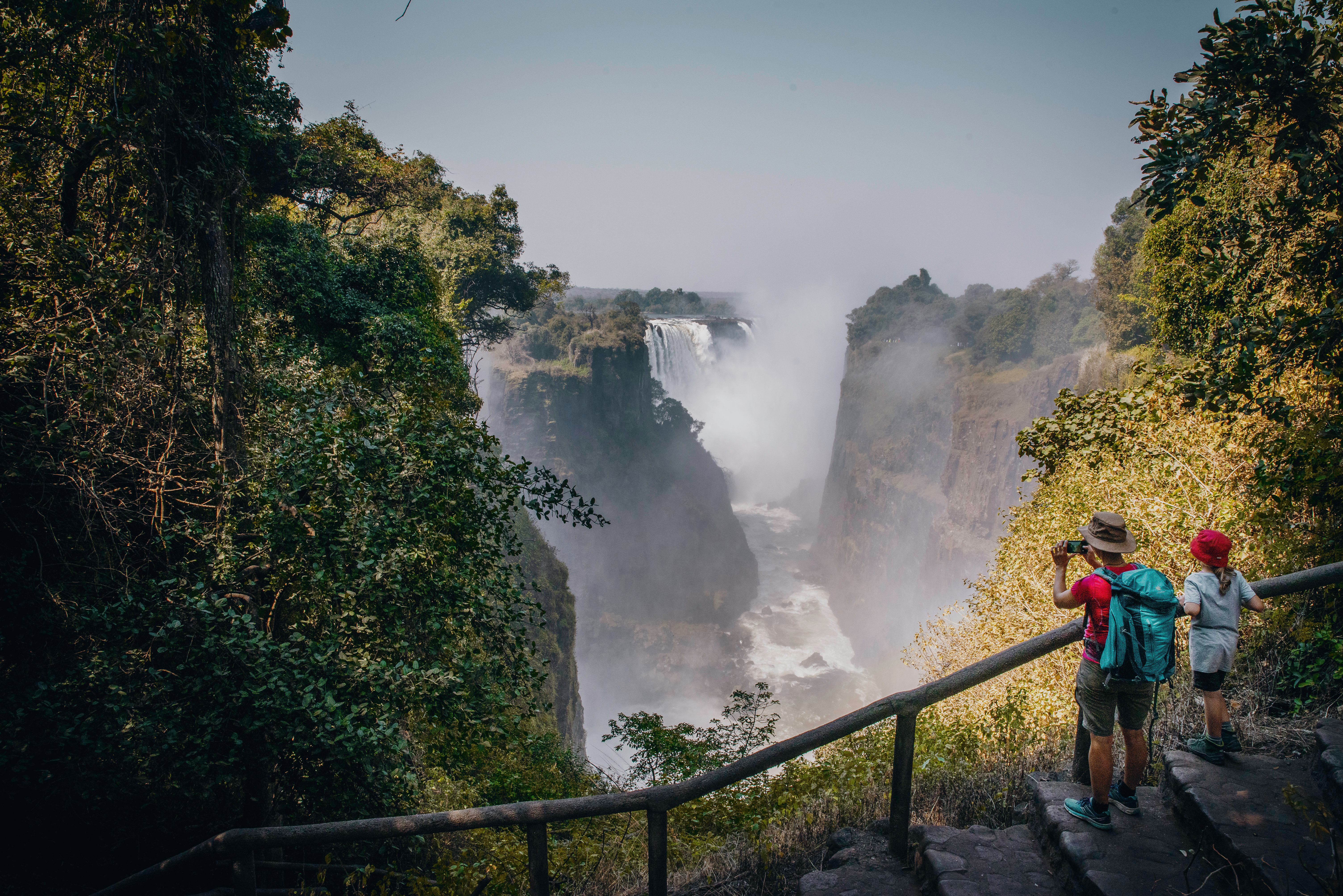 Two visitors photographing Victoria Falls spray from gorge viewpoint