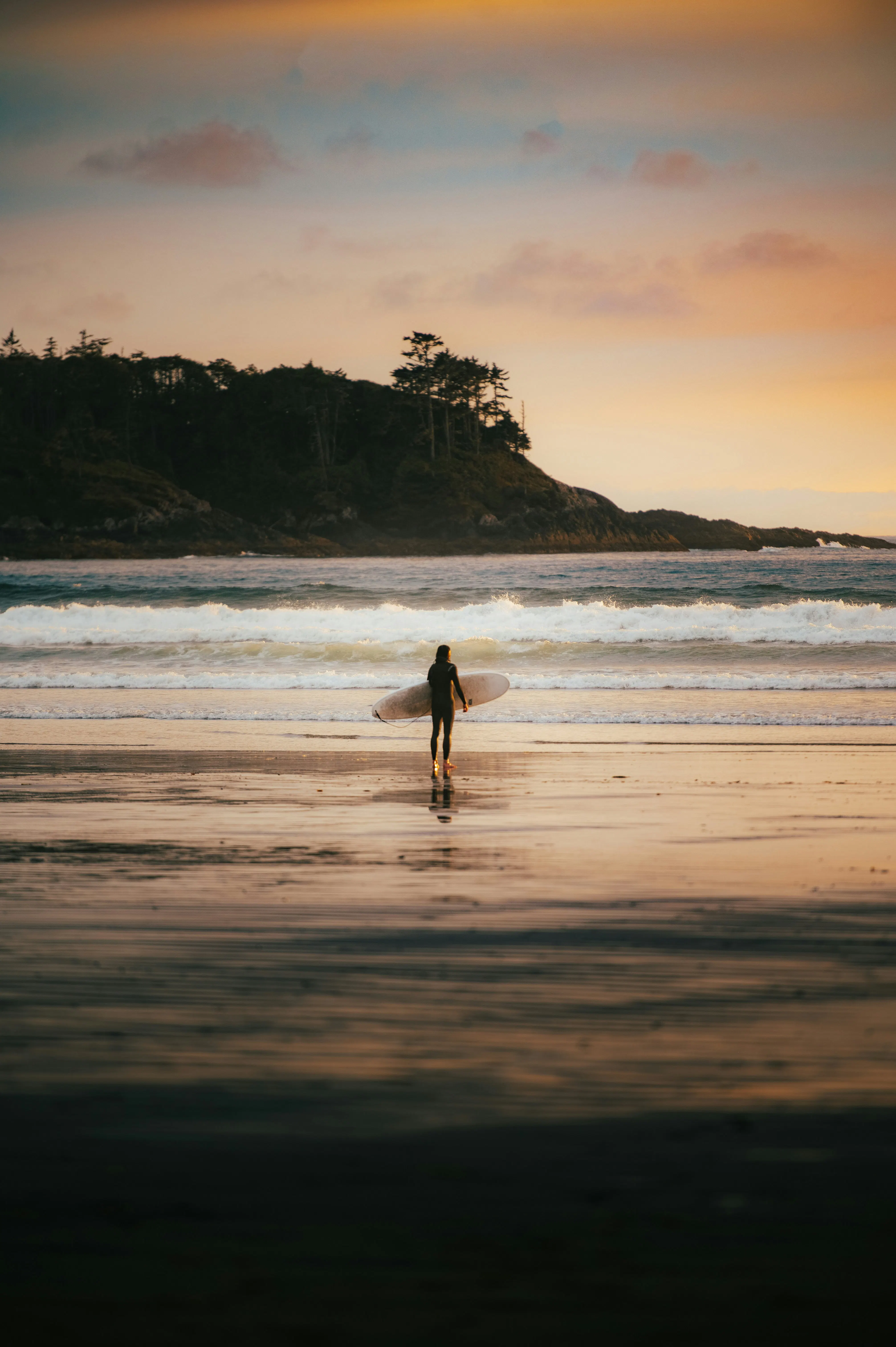 Surfer walking along the beach at sunset near Bocas del Toro, Panama