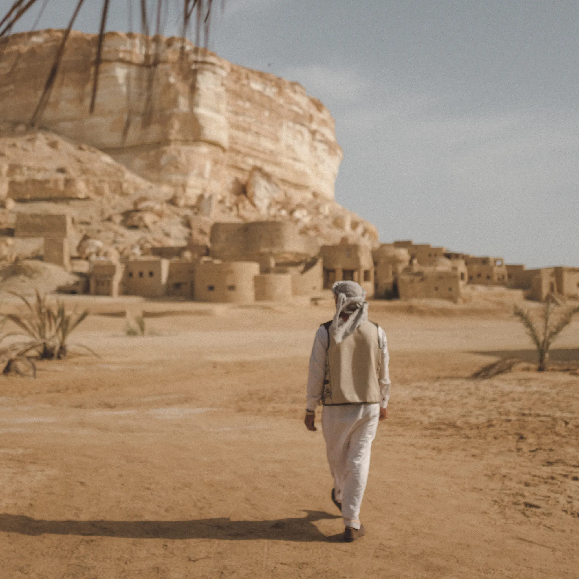 Local guide walking toward ancient mud-brick ruins, Egypt