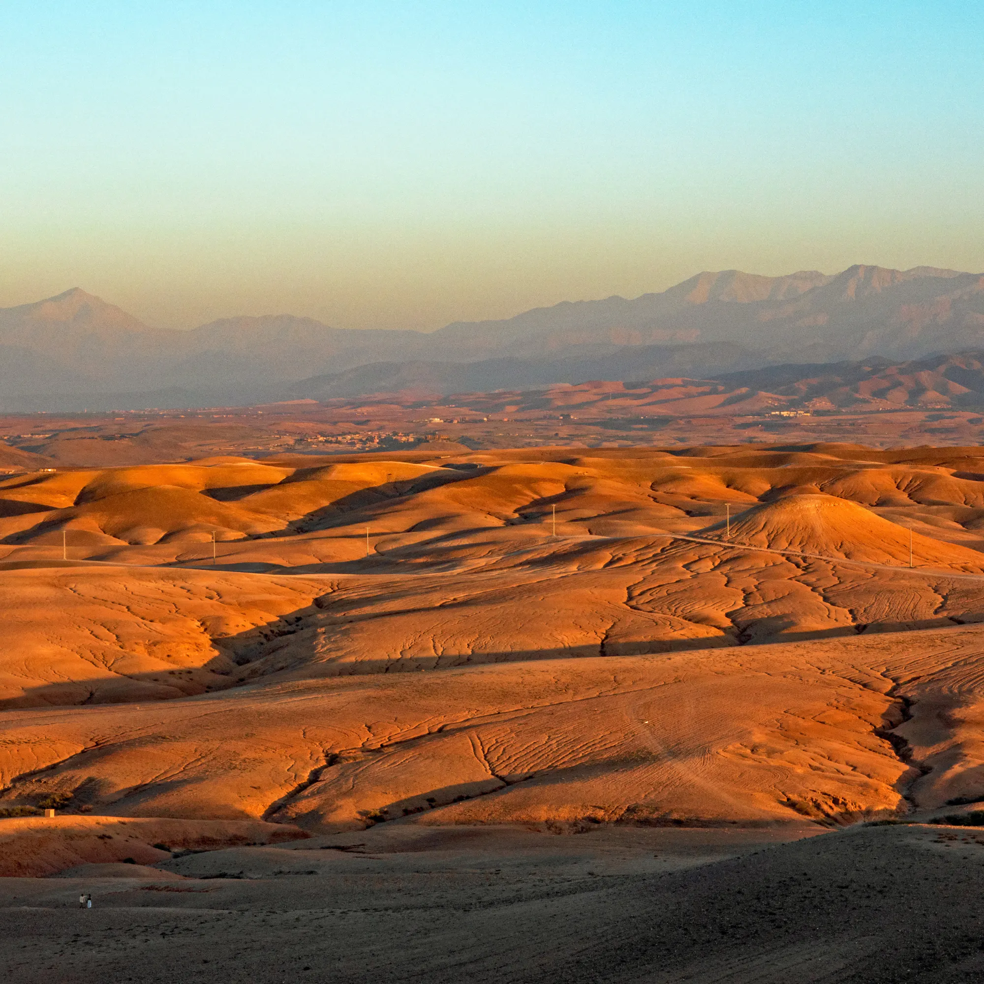 Golden rolling hills with the Atlas Mountains at sunset in Morocco