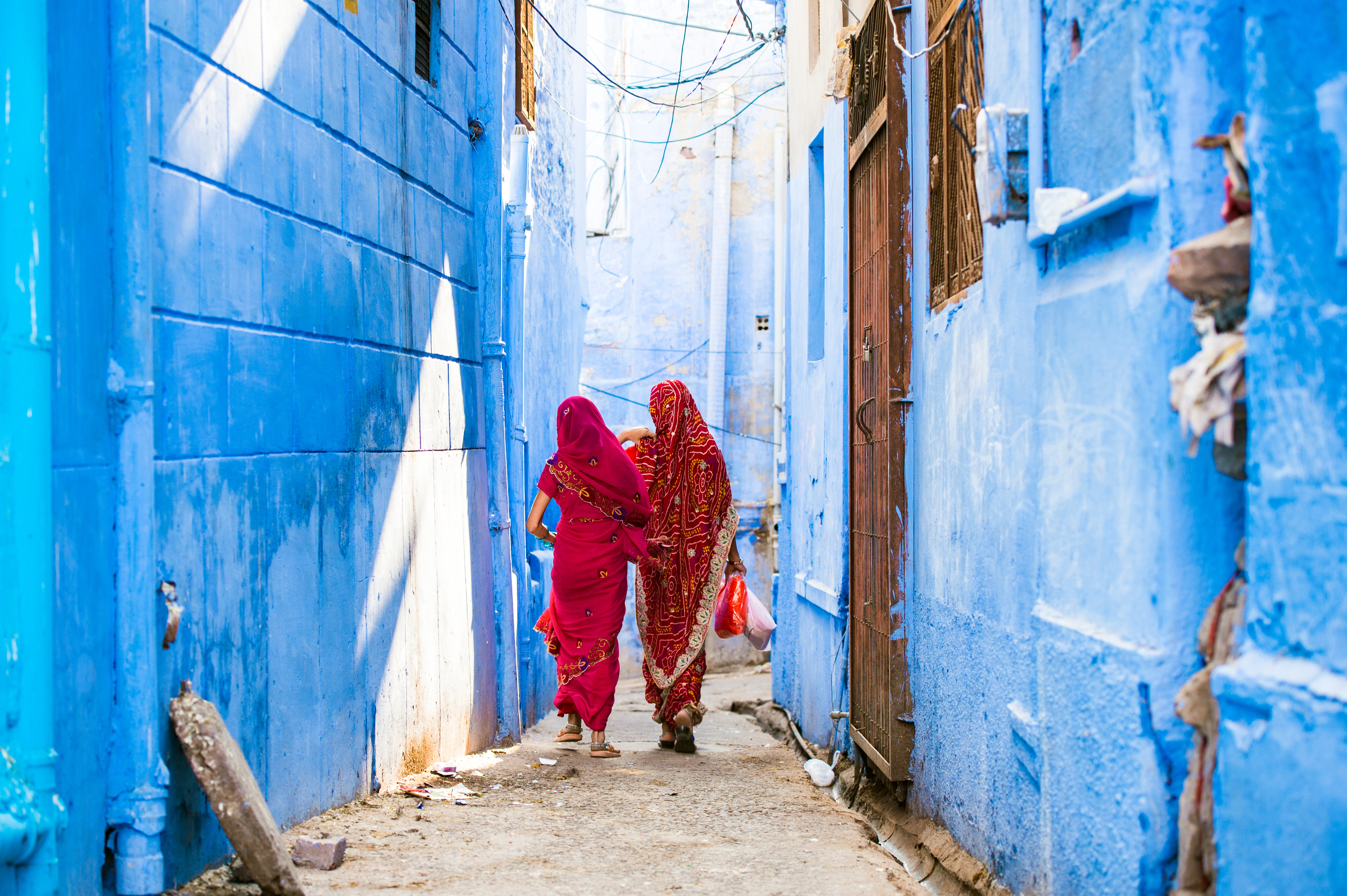 Women in saris walking through the blue lanes of Jodhpur, India