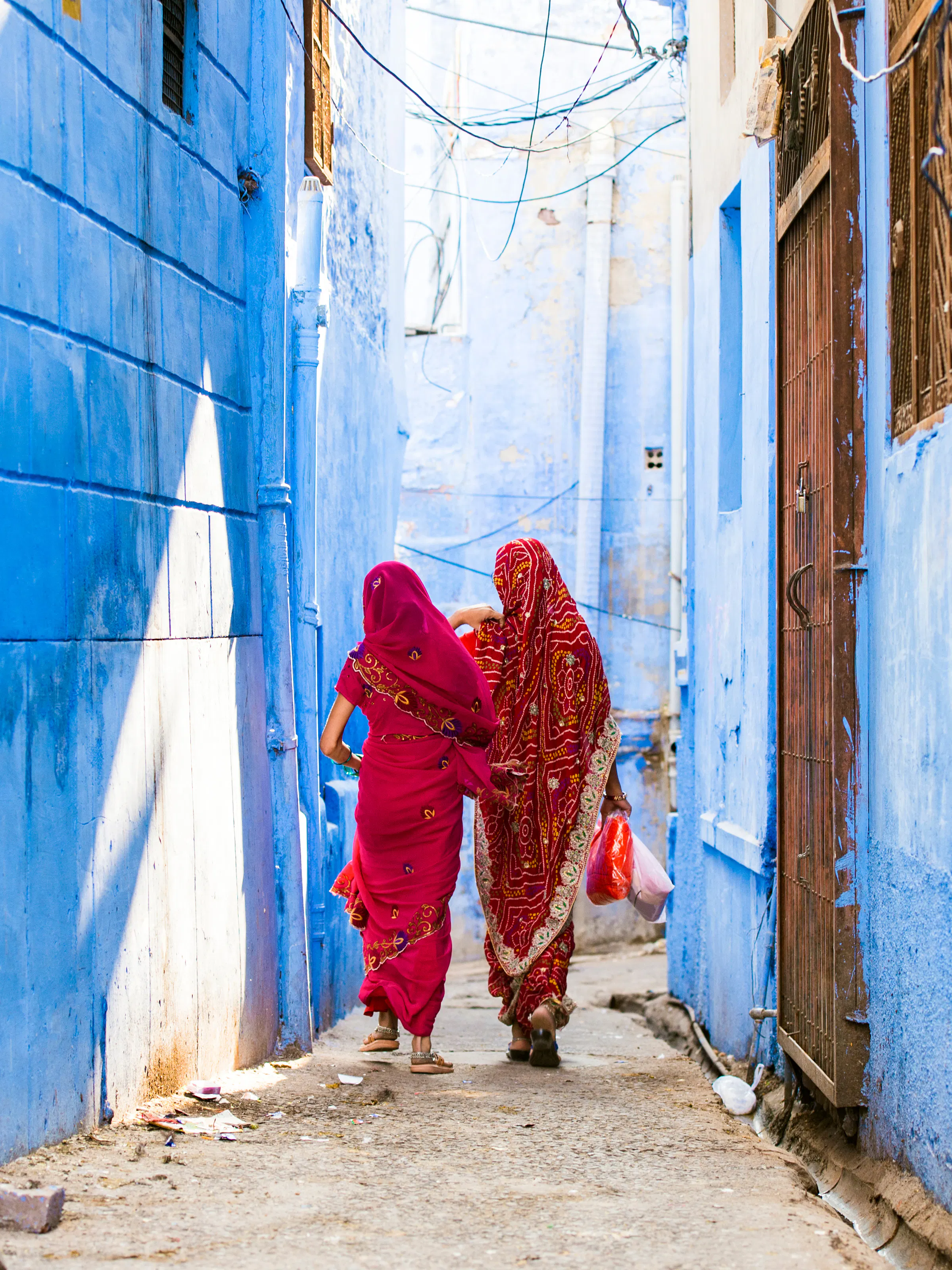Women in saris walking through the blue lanes of Jodhpur, India