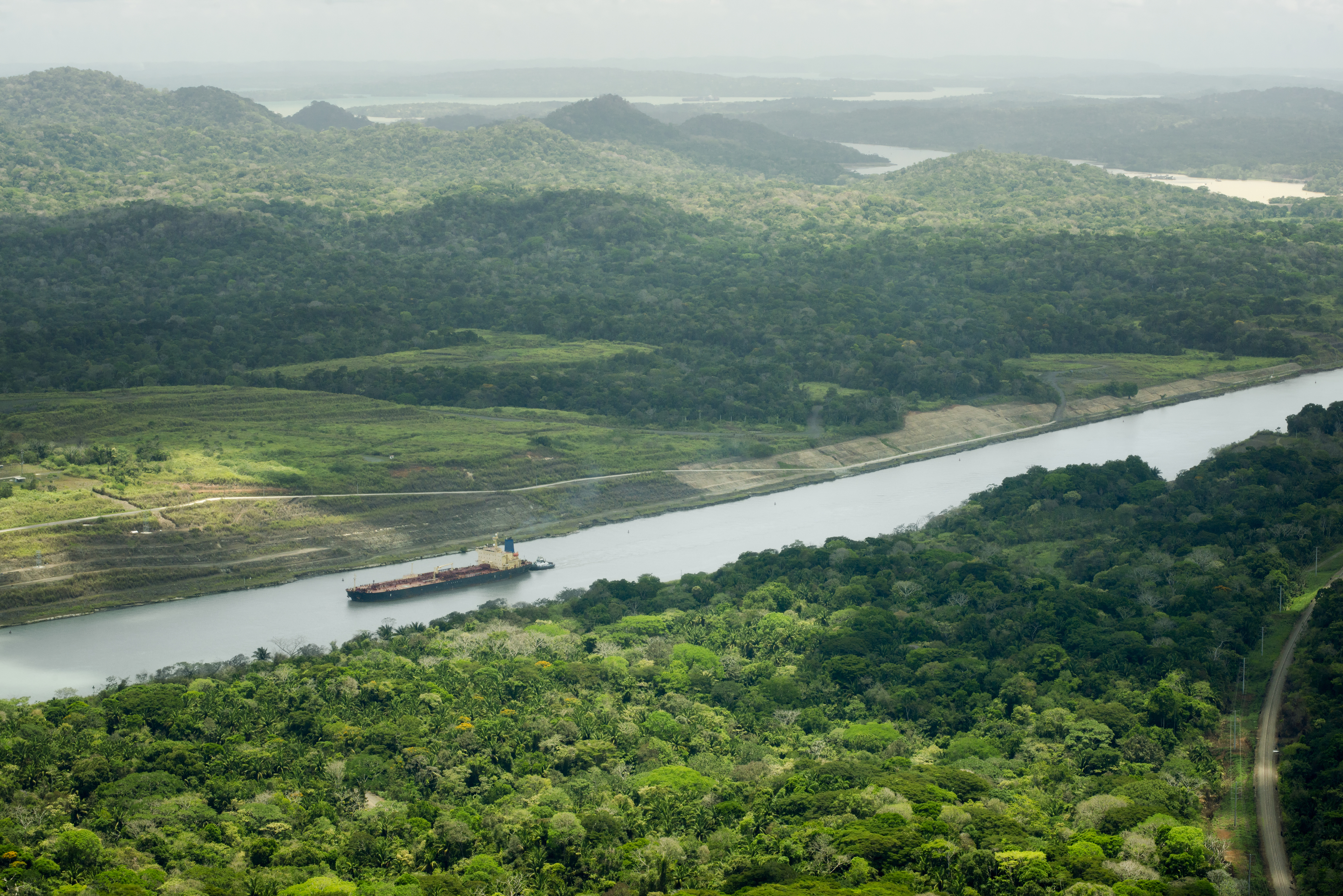 Aerial view of a cargo ship transiting the Panama Canal through rainforest