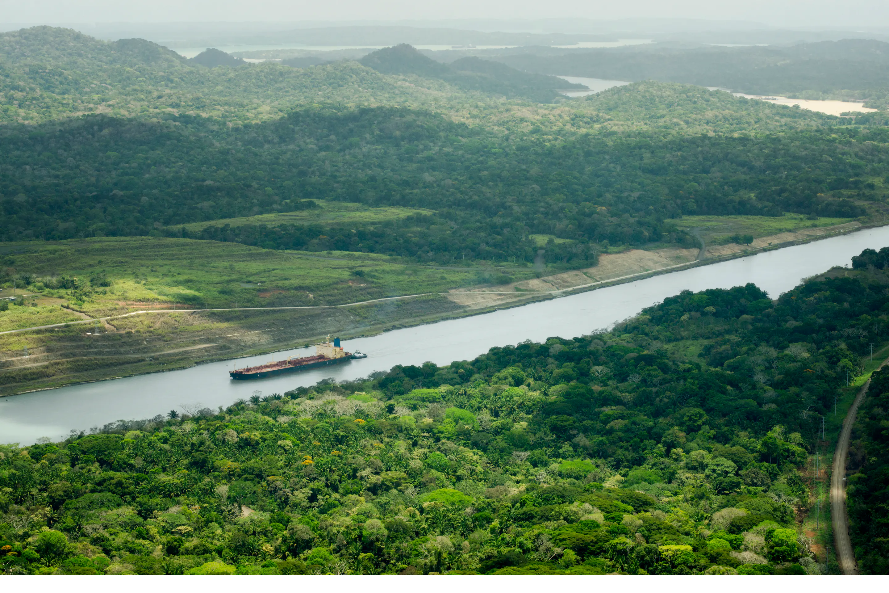 Aerial view of a cargo ship transiting the Panama Canal through rainforest