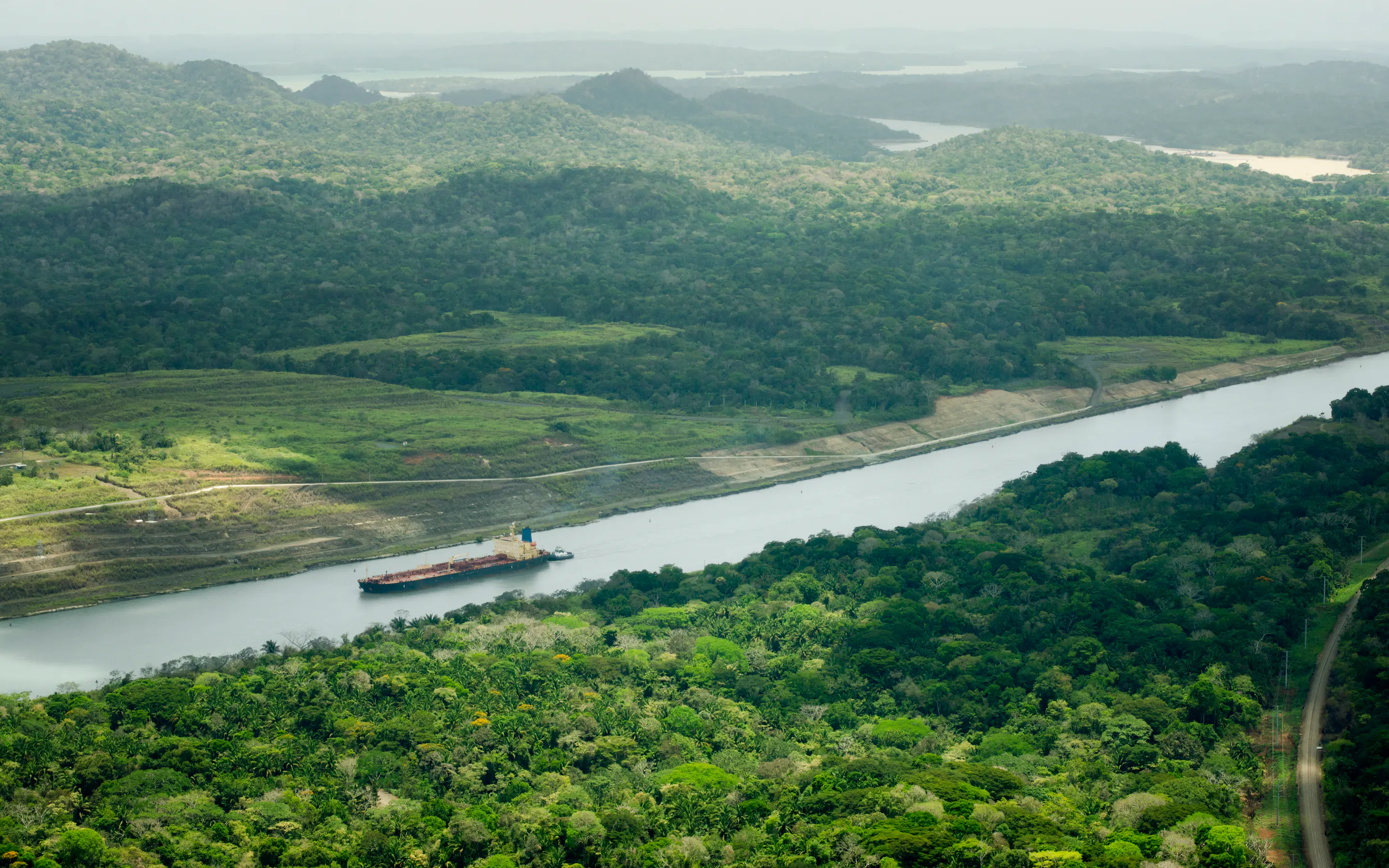 Aerial view of a cargo ship transiting the Panama Canal through rainforest