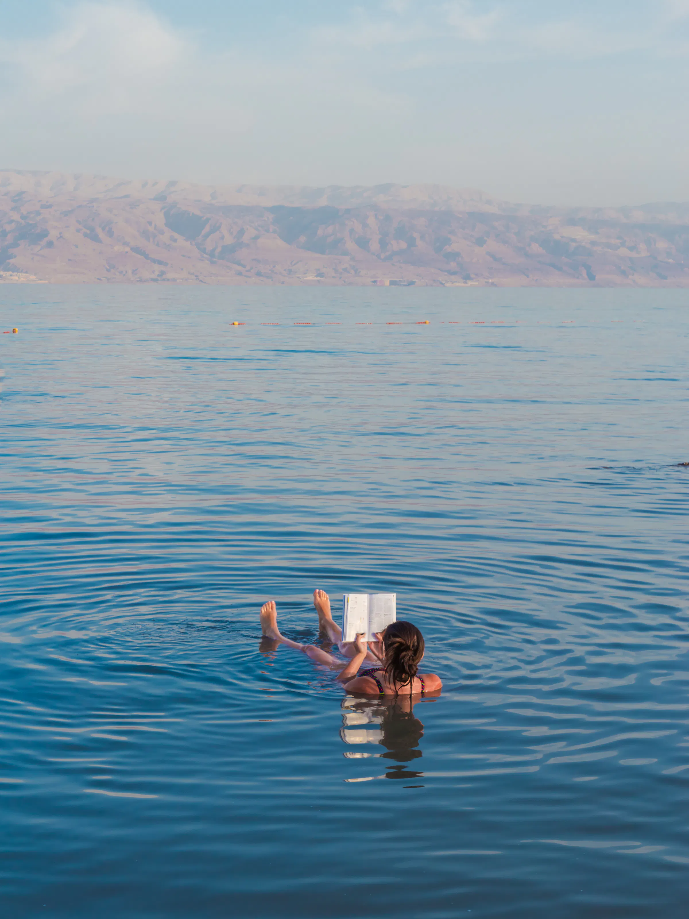 Woman reading a book while floating in the Dead Sea, Jordan