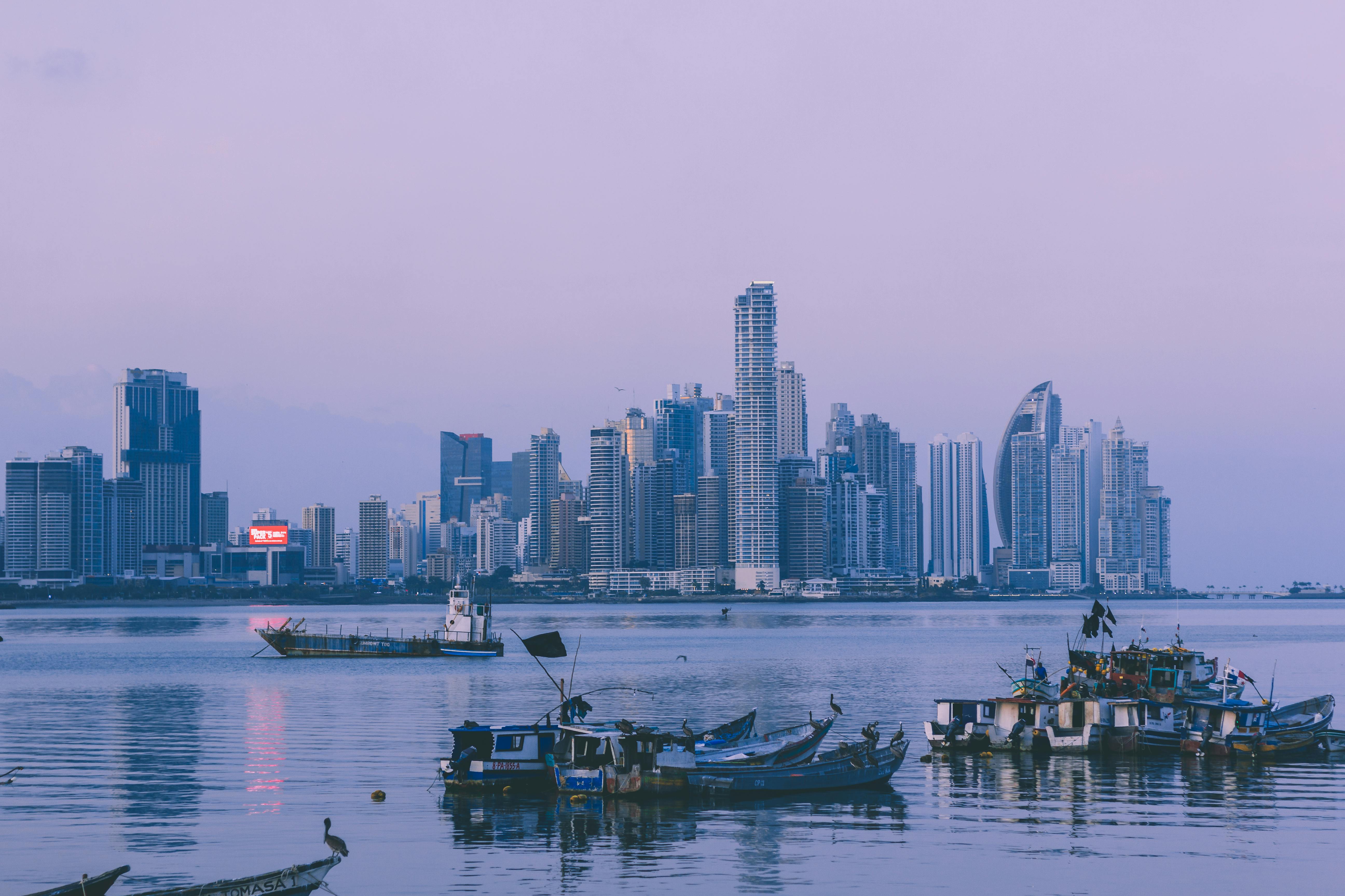 Panama City skyline at dusk with fishing boats in the foreground.