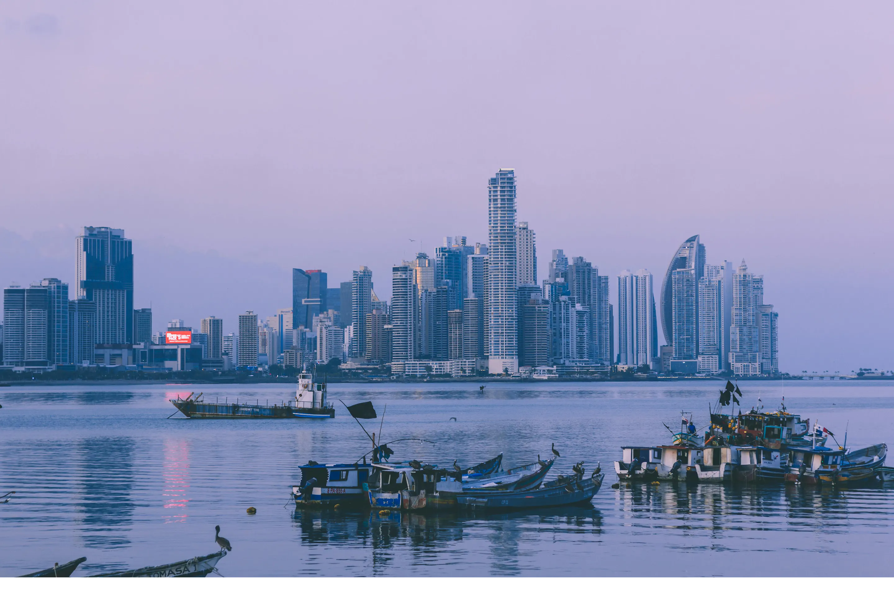 Panama City skyline at dusk with fishing boats in the foreground.