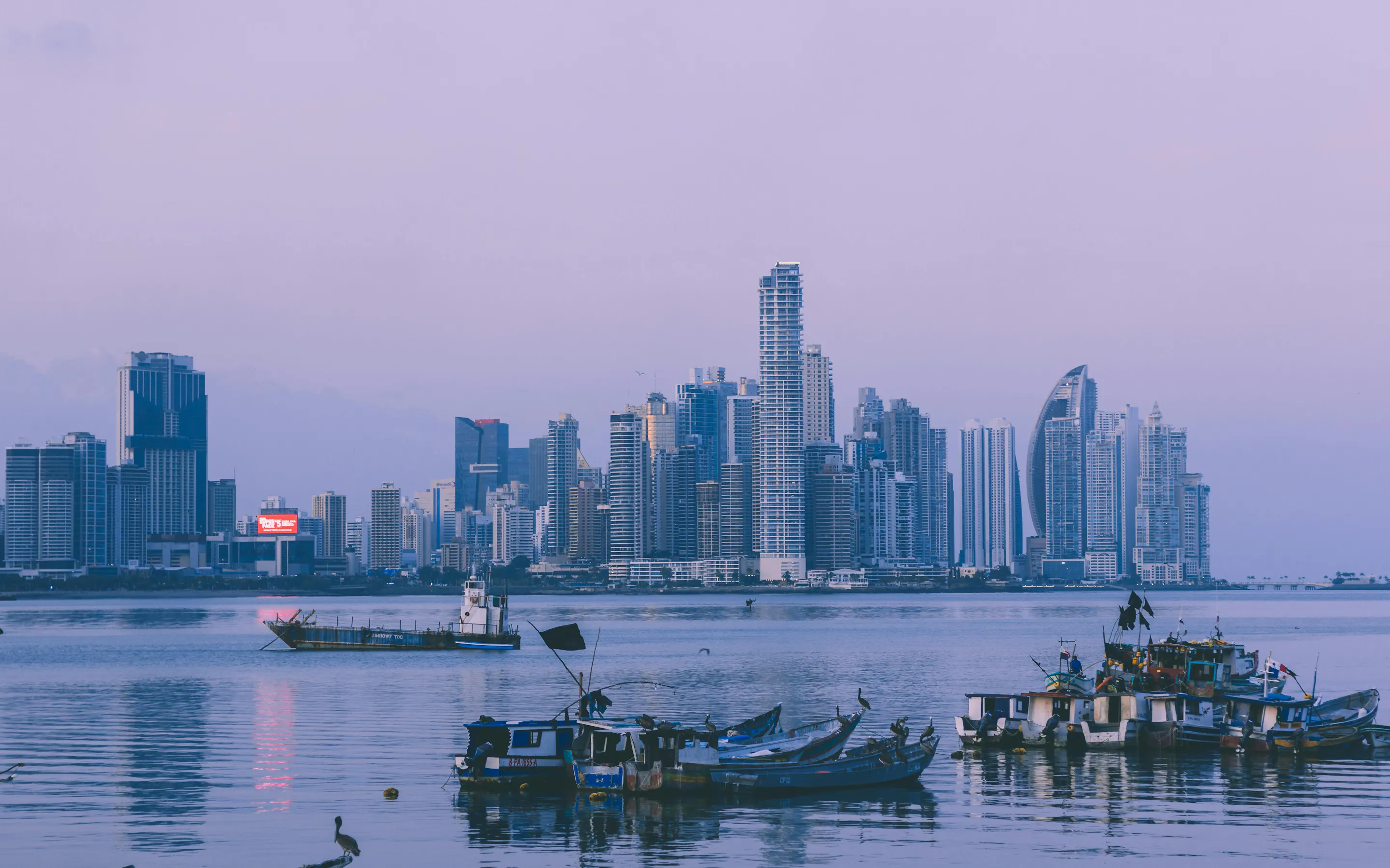 Panama City skyline at dusk with fishing boats in the foreground.