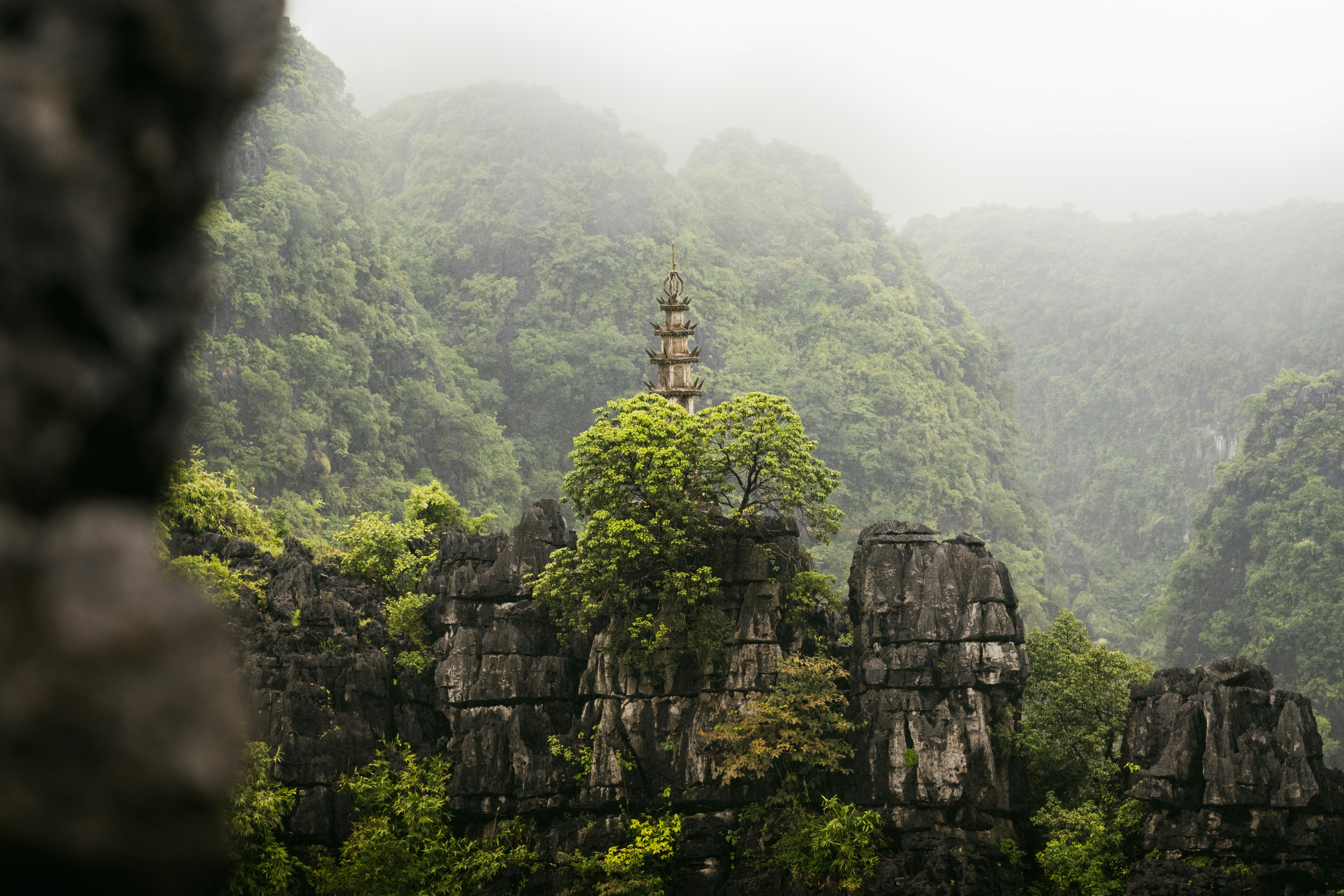 Ancient pagoda rising through misty limestone rocks, Ninh Binh Vietnam
