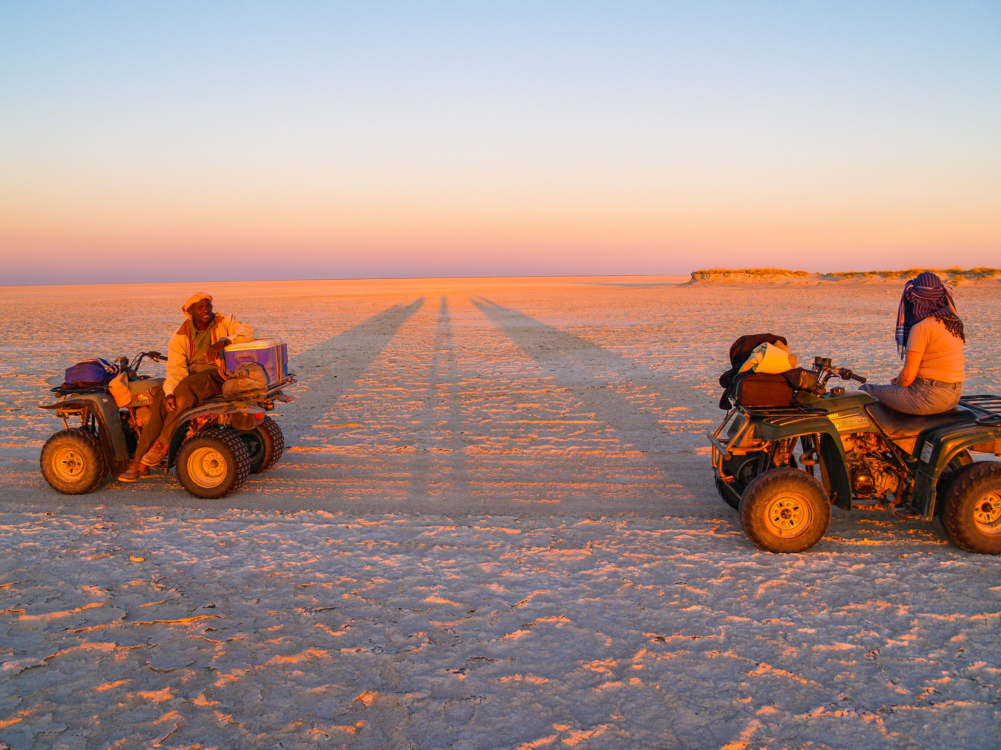 Quad bikers crossing the salt pans at sunset in Nxai Pan National Park, Botswana