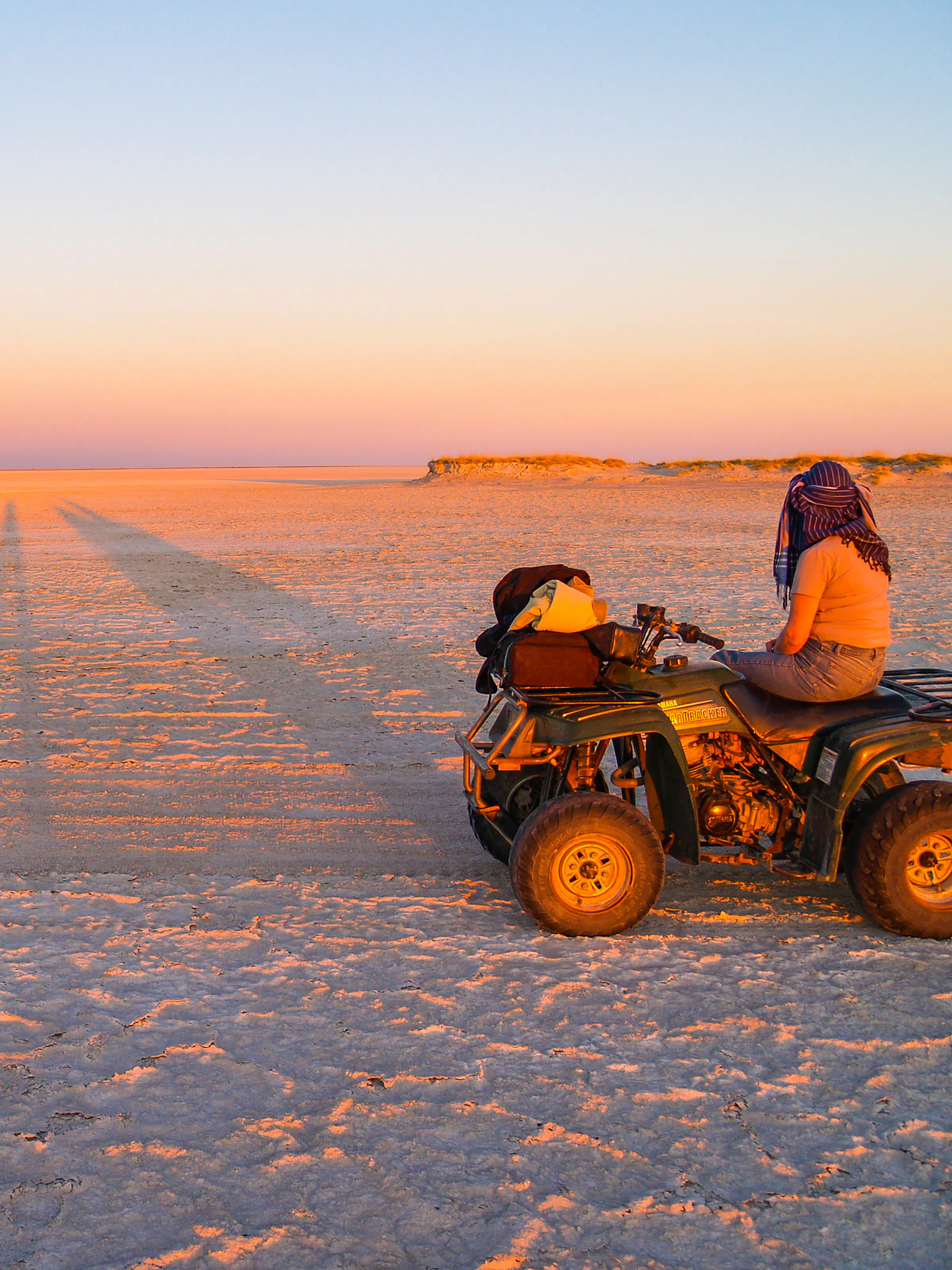 Quad bikers crossing the salt pans at sunset in Nxai Pan National Park, Botswana