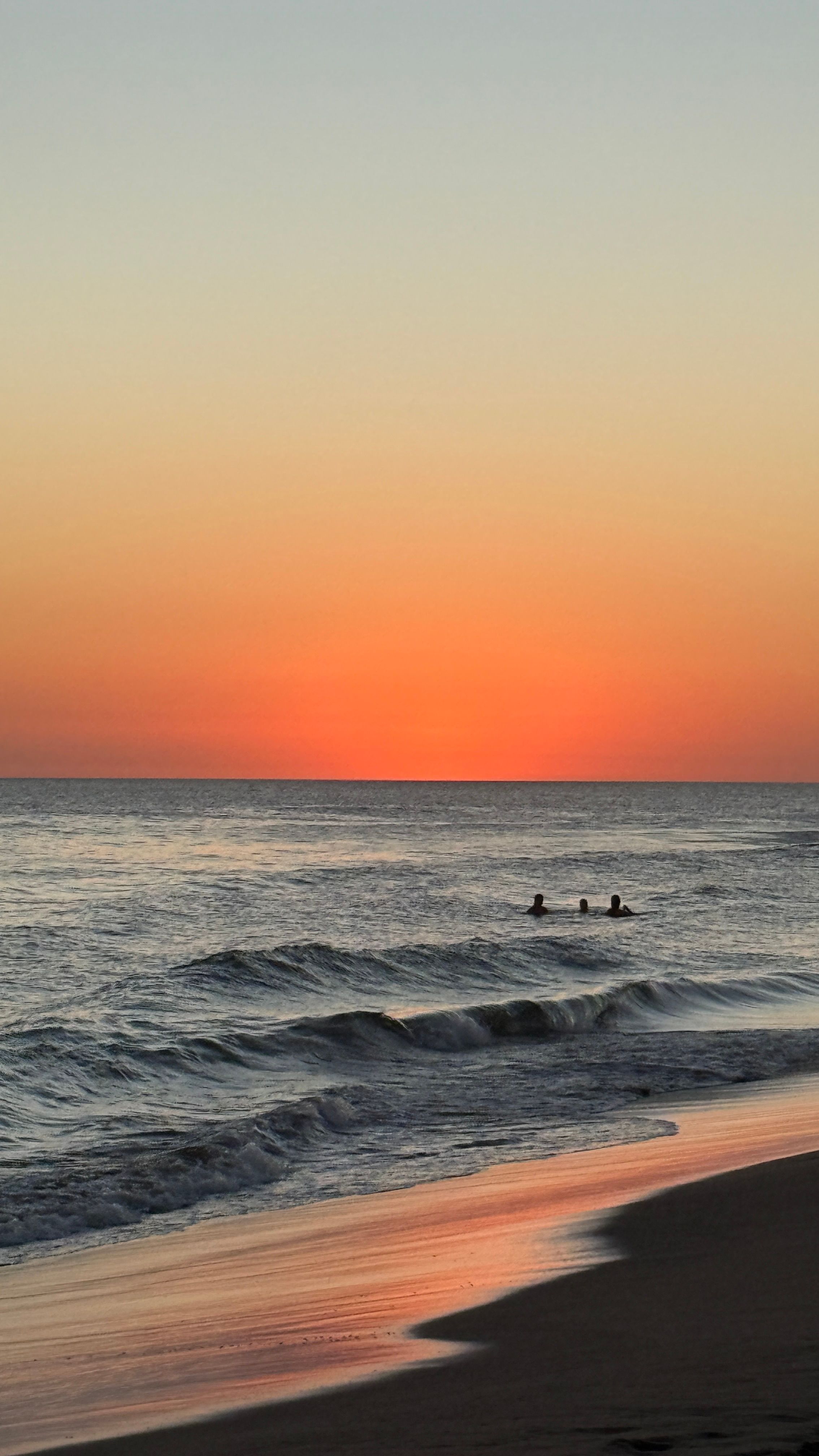 Swimmers silhouetted against a sunset over the ocean in José Ignacio, Uruguay
