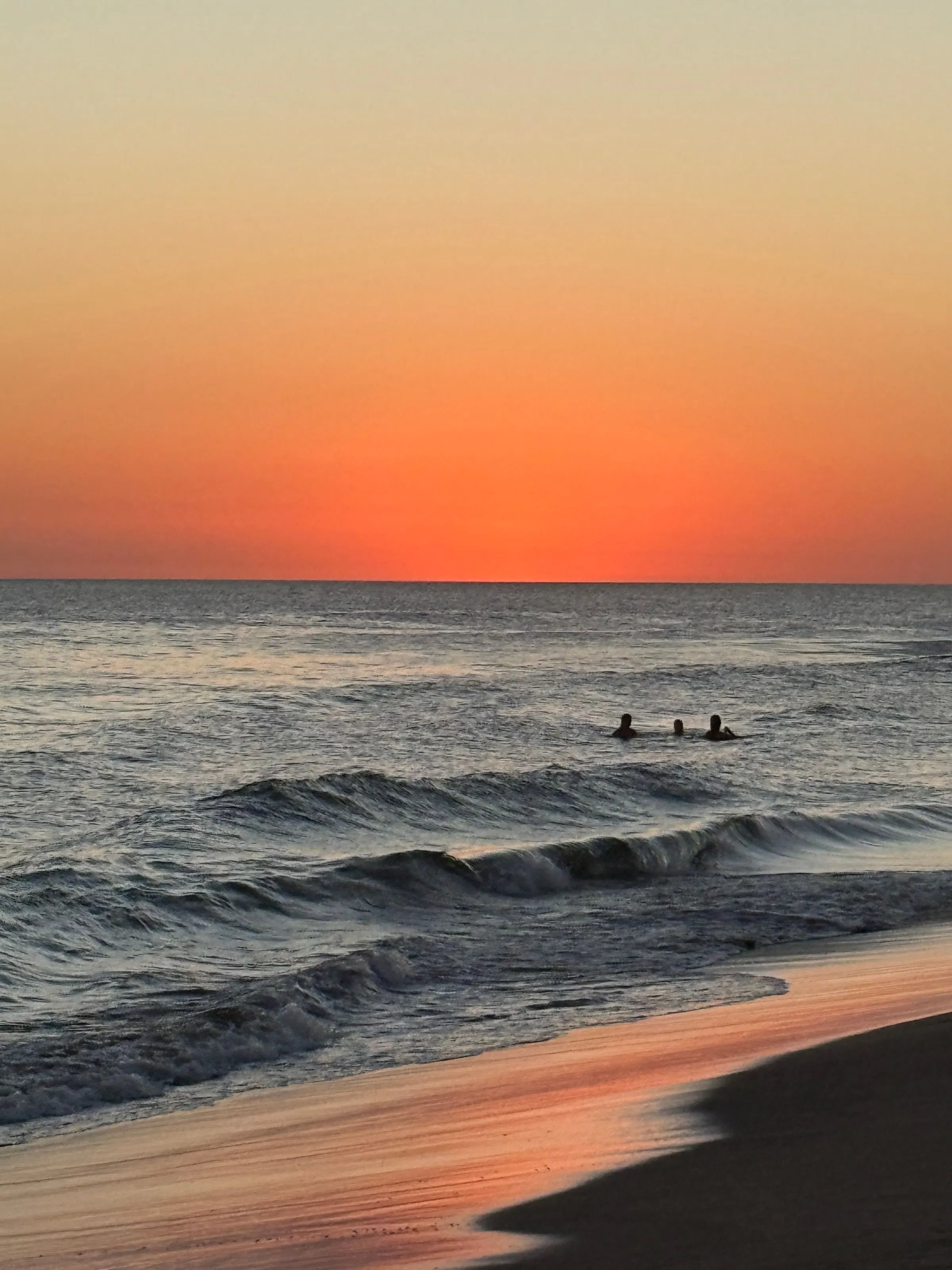 Swimmers silhouetted against a sunset over the ocean in José Ignacio, Uruguay