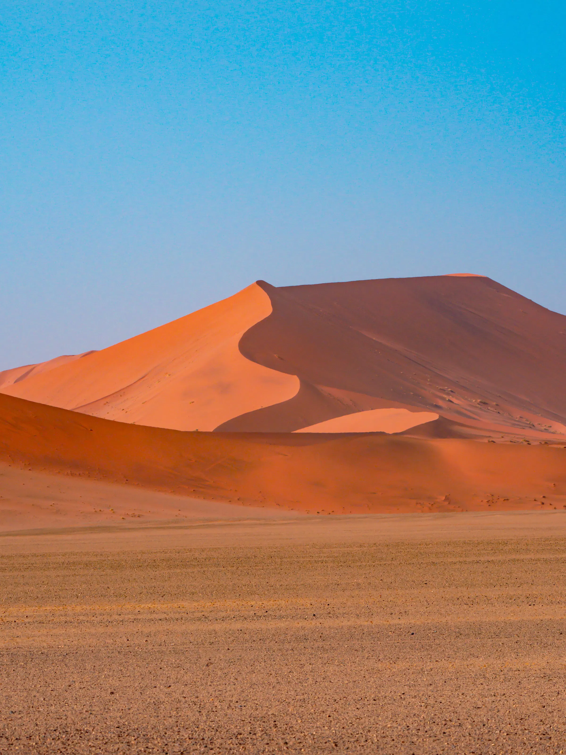 Towering red sand dune with sharp ridgeline in Sossusvlei, Namibia