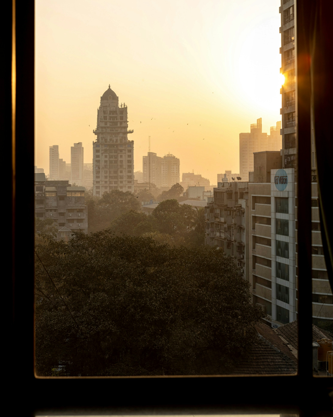 The Mumbai skyline captured through a window at sunset