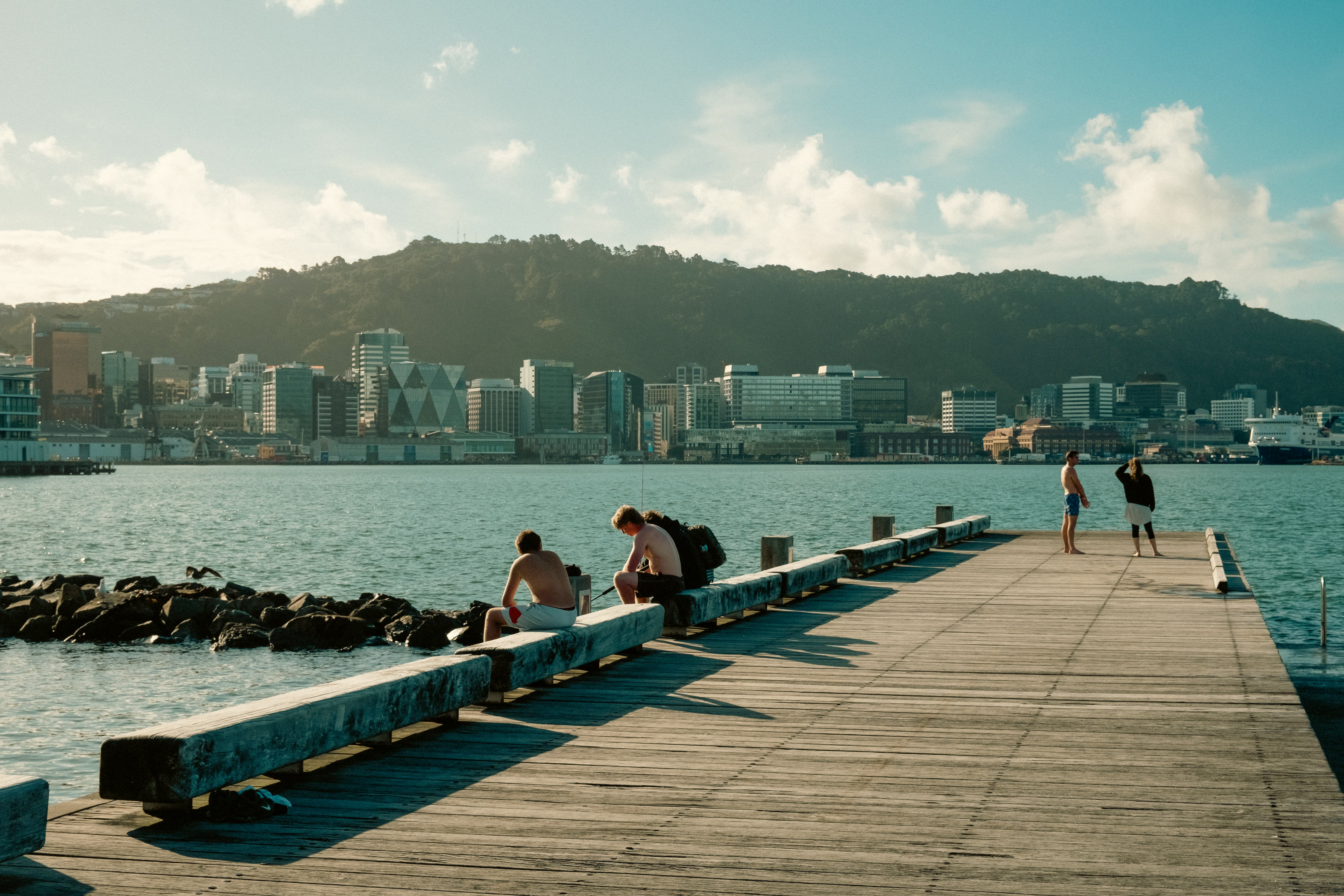 People relaxing on waterfront pier with Wellington CBD skyline beyond