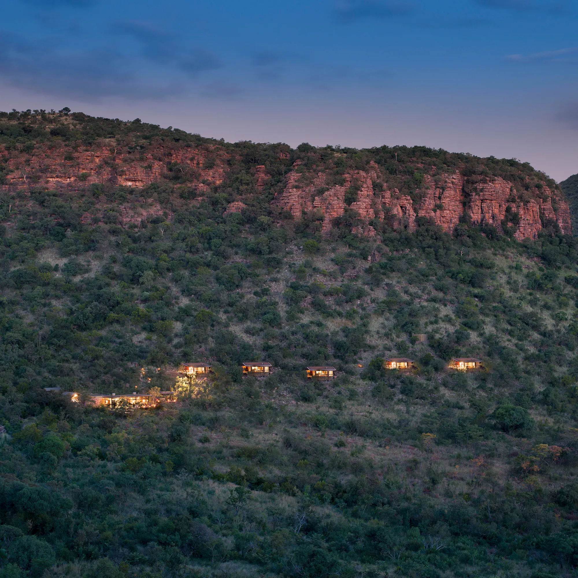 Marataba Walking Trails Lodge chalets illuminated at dusk in the Waterberg mountains, South Africa