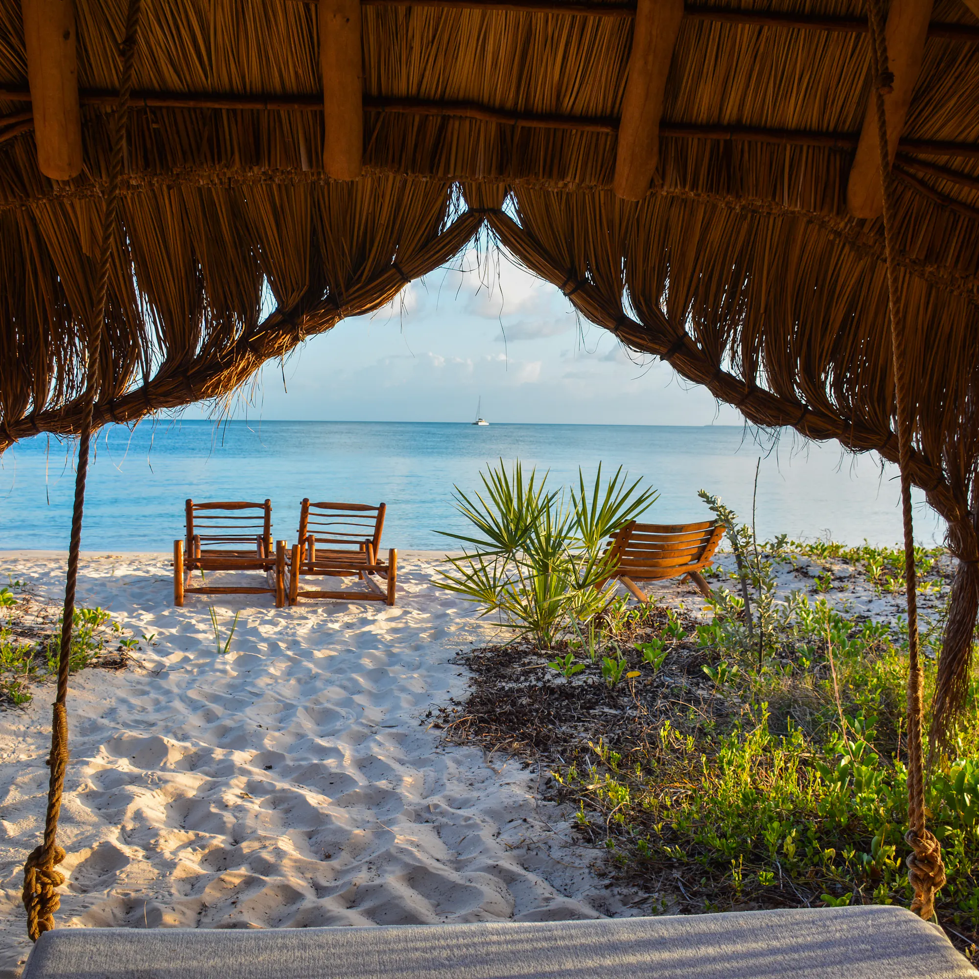 Thatched beach gazebo with wooden chairs overlooking Indian Ocean