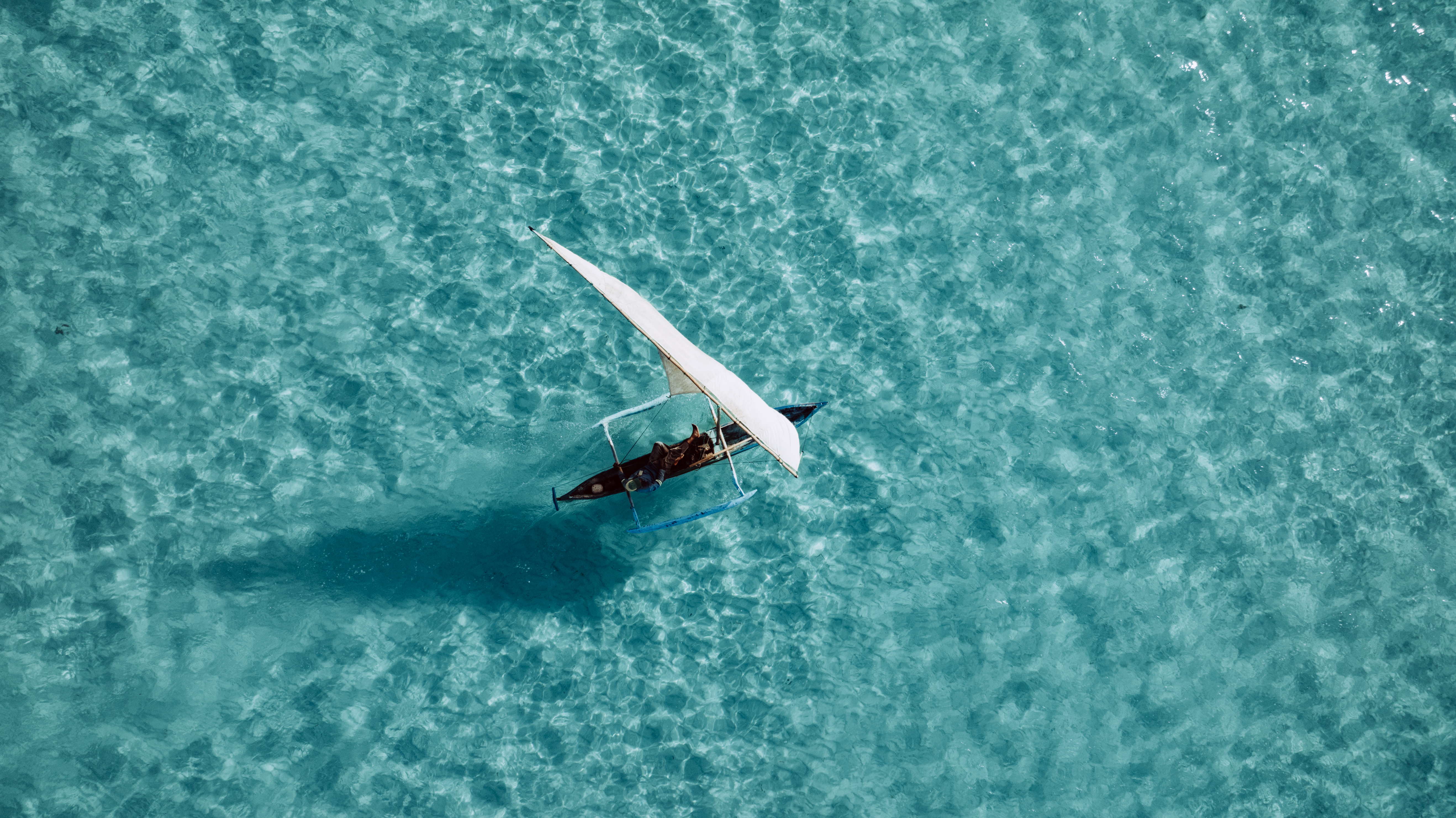 Image 3 — Aerial dhow on turquoise water
Aerial view of traditional dhow sailing crystal waters