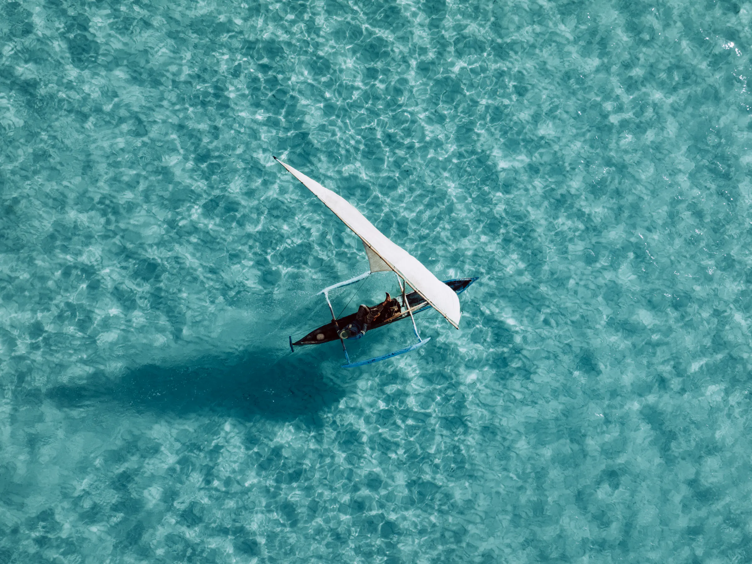 Image 3 — Aerial dhow on turquoise water
Aerial view of traditional dhow sailing crystal waters