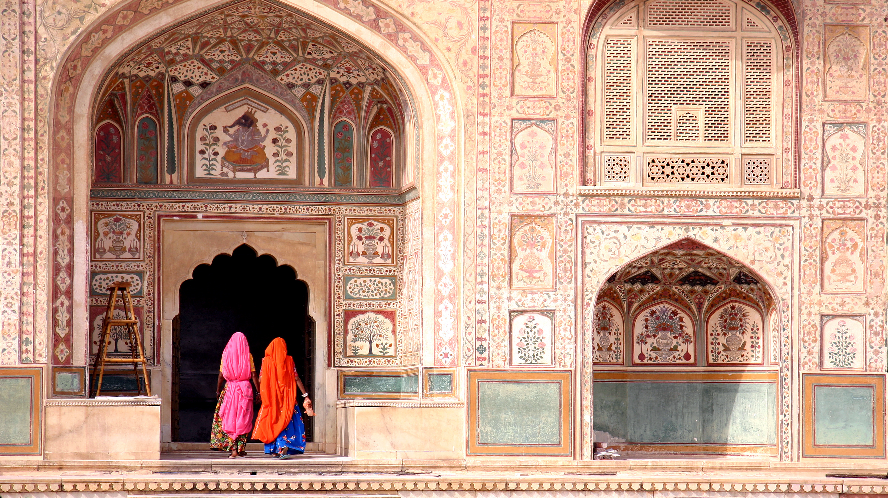 Women in colorful saris entering ornate Amber Fort, Jaipur