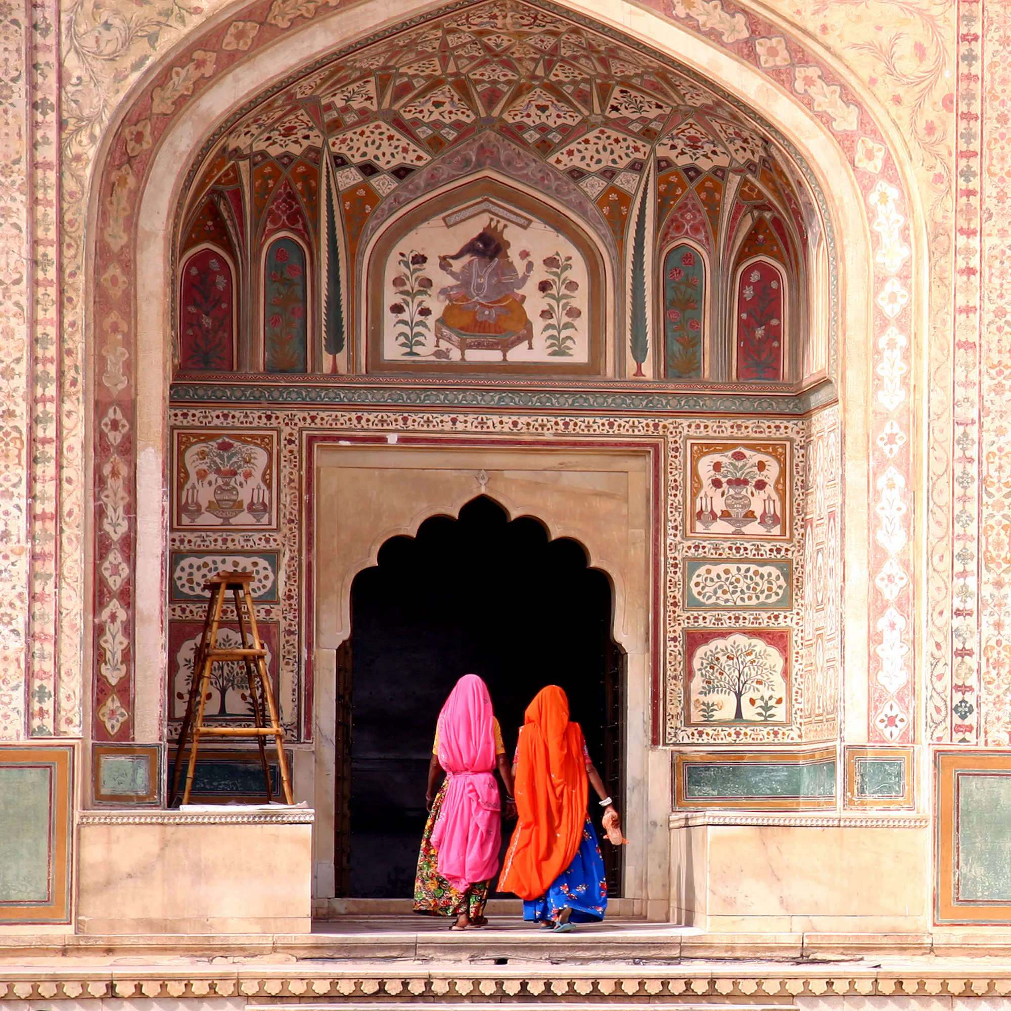 Women in colorful saris entering ornate Amber Fort, Jaipur